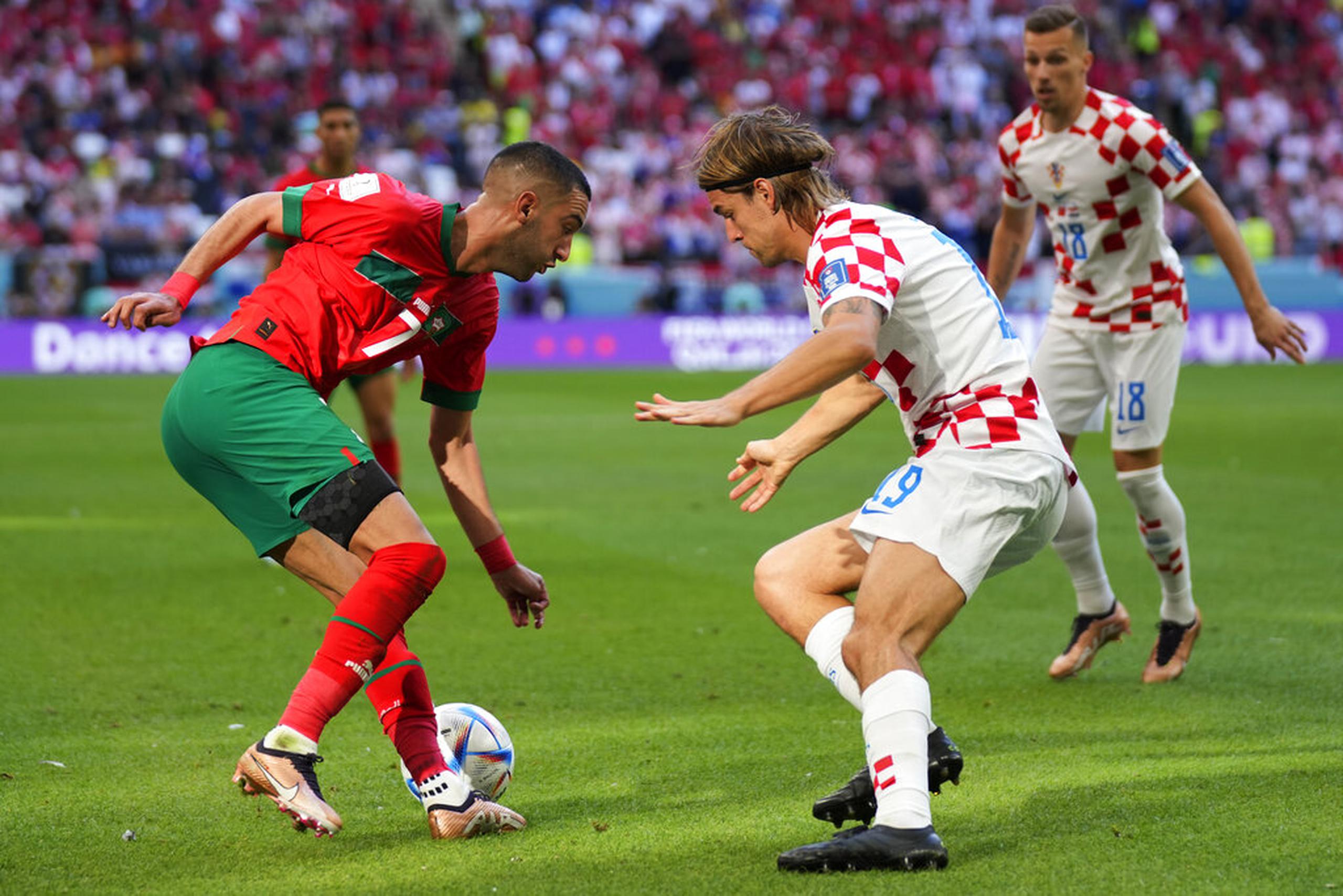 El croata Borna Sosa (centro) y el marroquí Hakim Ziyech disputan el balón durante el partido por el Grupo F del Mundial en el estadio Al Bayt en Jor, Qatar.