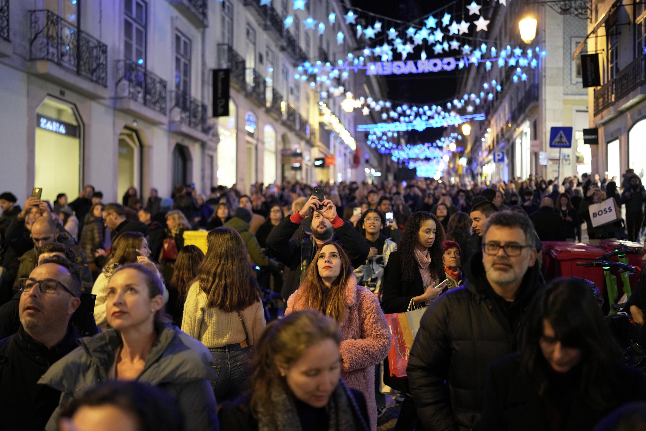 Varias personas contemplan las luces de Navidad en el barrio de Chiado, en el centro de Lisboa, Portugal, el sábado 23 de diciembre de 2023. (AP Foto/Armando Franca)