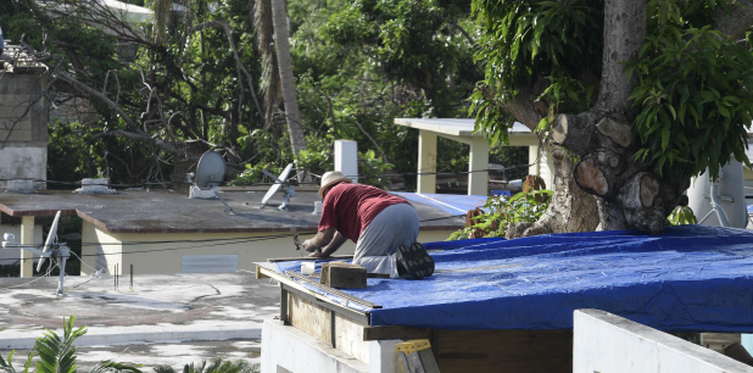 Un ciudadano de Yabucoa hace dos semanas colocaba un toldo para sustituir el techo que se llevó María. (Archivo)