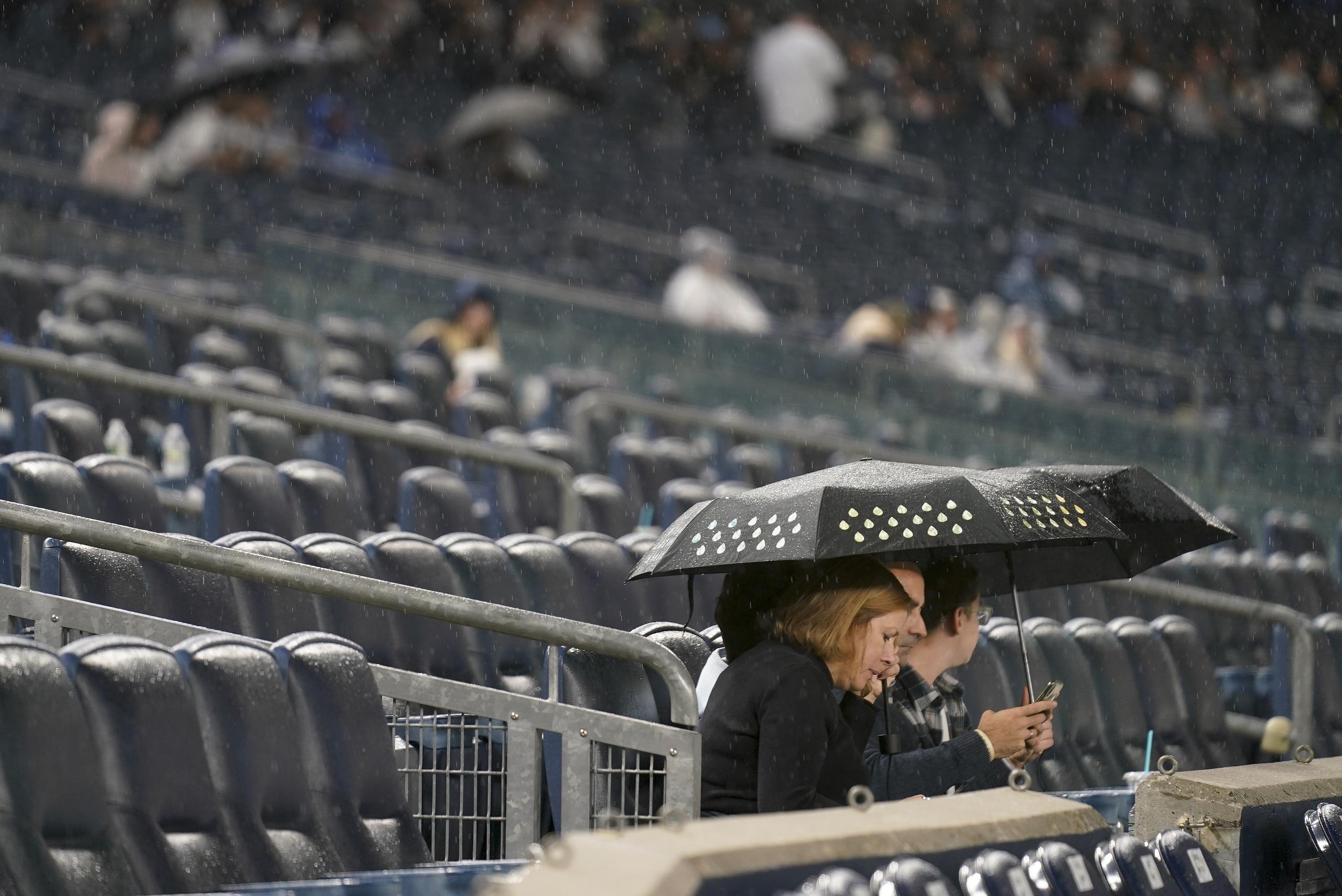 Algunos fanáticos en el Yankee Stadium se quedaron esperando bajo la lluvia por el inicio del partido Cleveland-Nueva York, que fue pospuesto para este martes en la tarde.