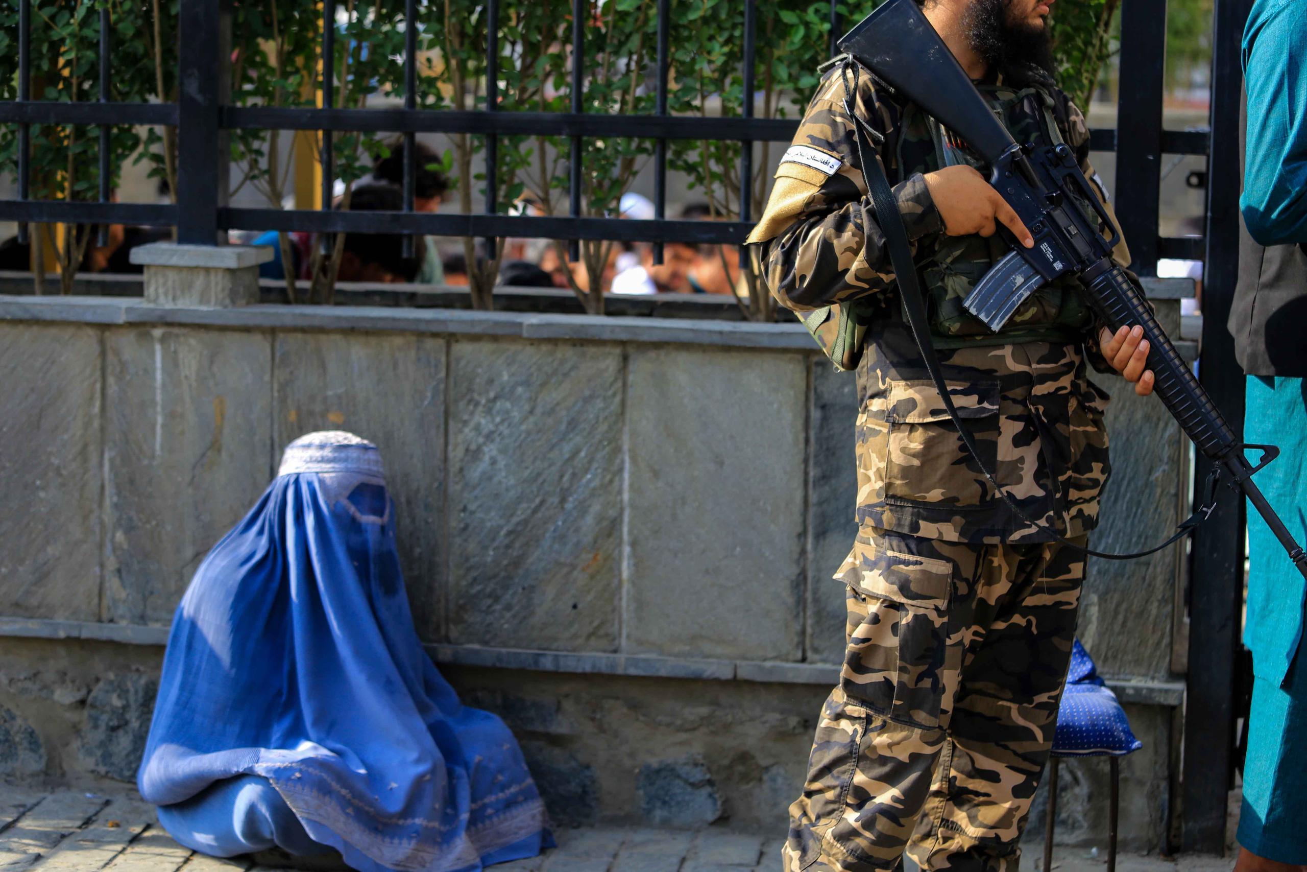Una mujer afgana vestida con burka pide limosna mientras los talibanes hacen guardia en un lugar público en Kabul el pasado 27 de julio. (EFE/EPA/STRINGER)