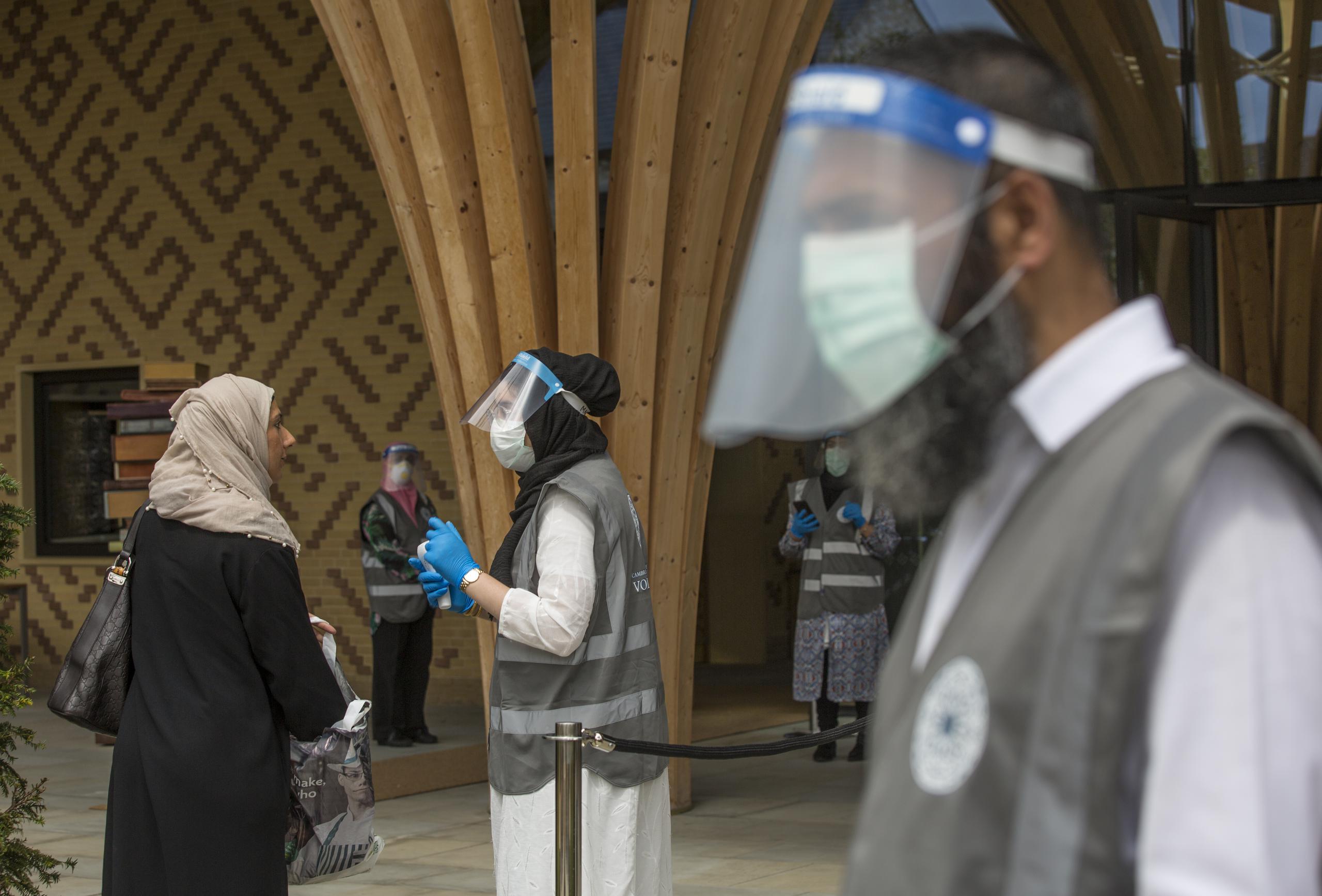 Voluntarios y personal de la Mezquita Central de Cambridge, Inglaterra, reciben a los feligreses en el primer oficio de los viernes desde la cuarentena
