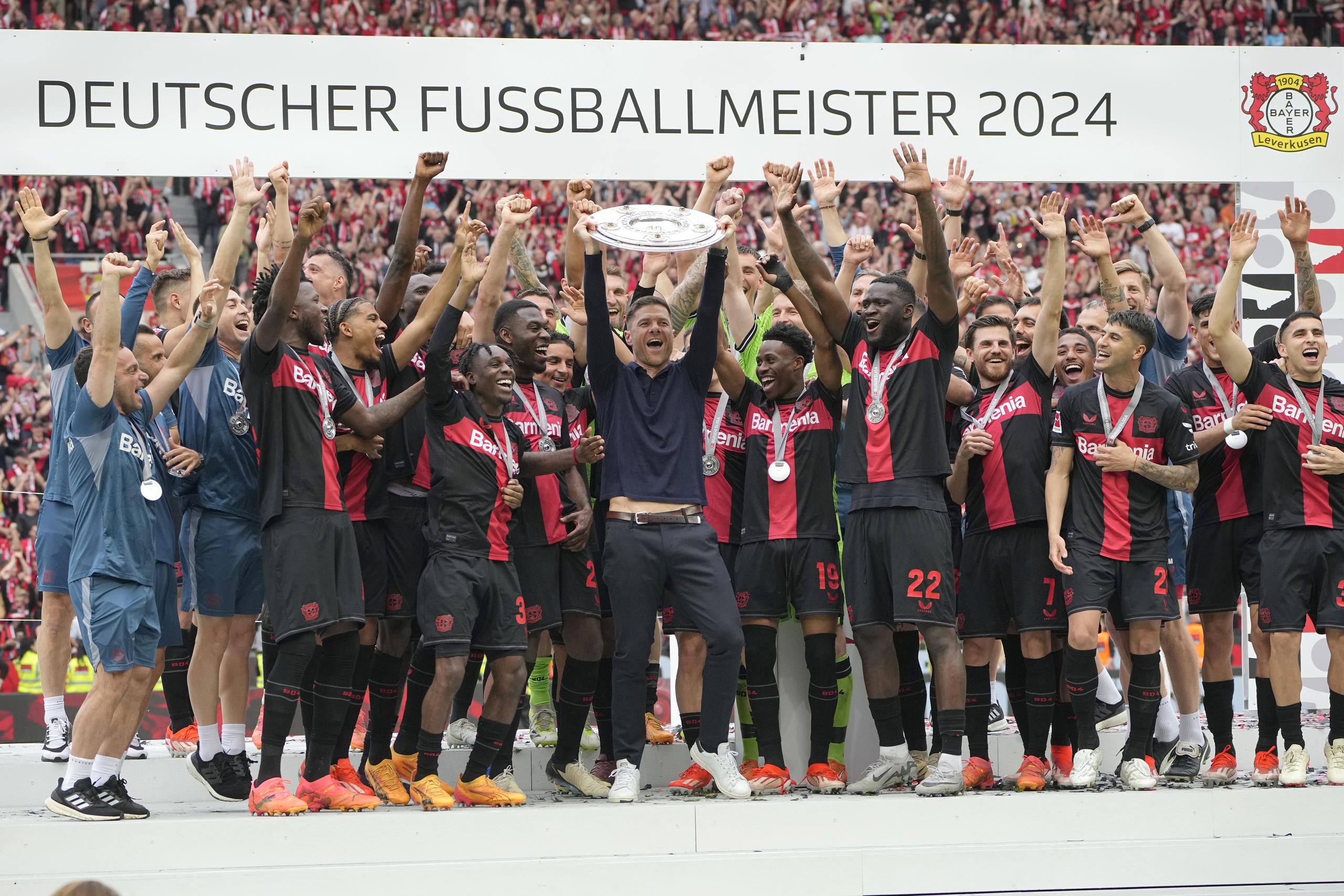 El técnico del Bayer Leverkusen, Xabi Alonso, celebra con el trofeo junto a sus jugadores tras ganar el título de la Bundesliga tras el juego ante el Augsburg.