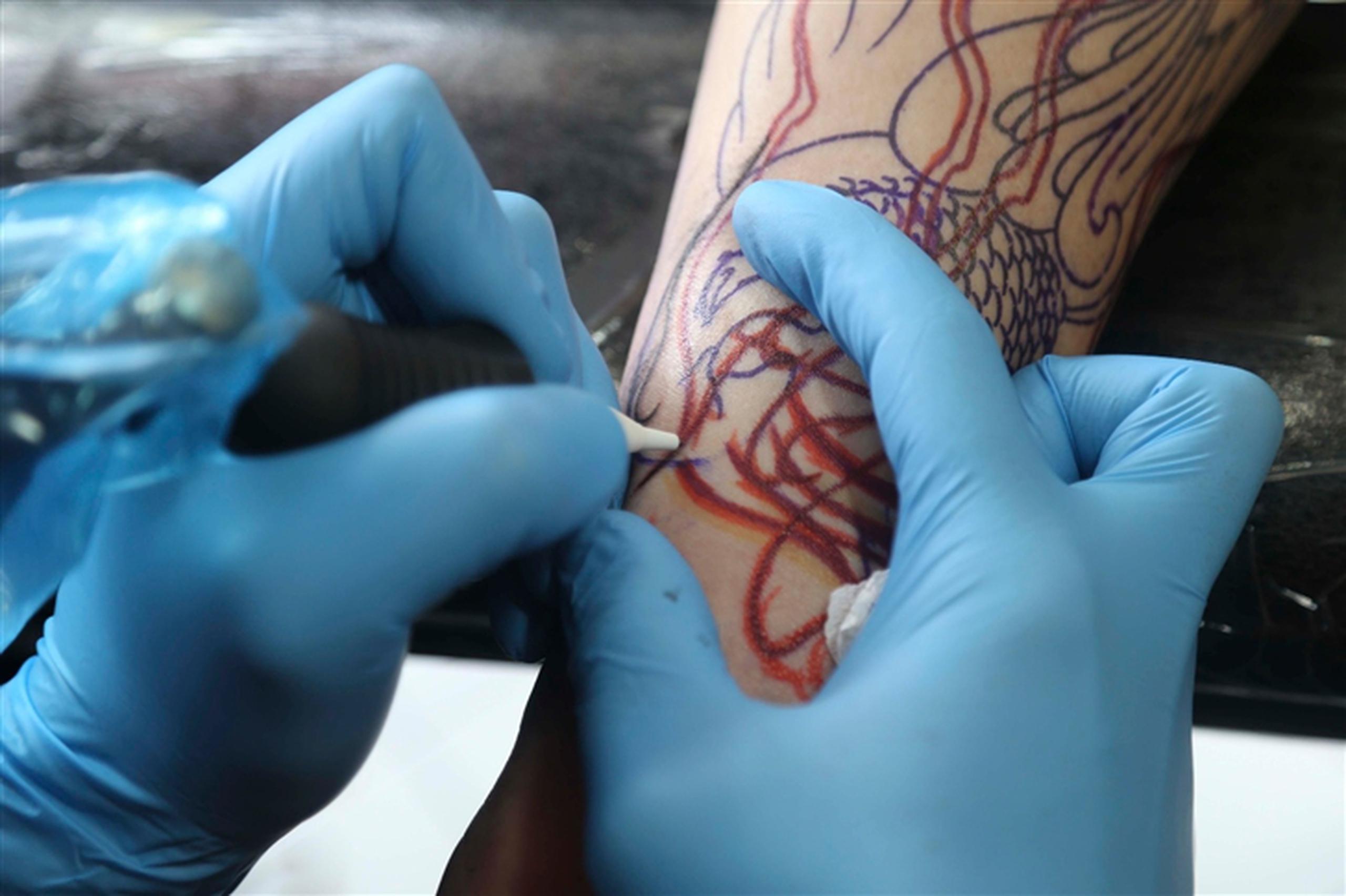 El artista Julio Rivera, de Body Temple Tattoo, le dibuja un nuevo tatuaje al pastor Martín López. (wandaliz.vega@gfrmedia.com)