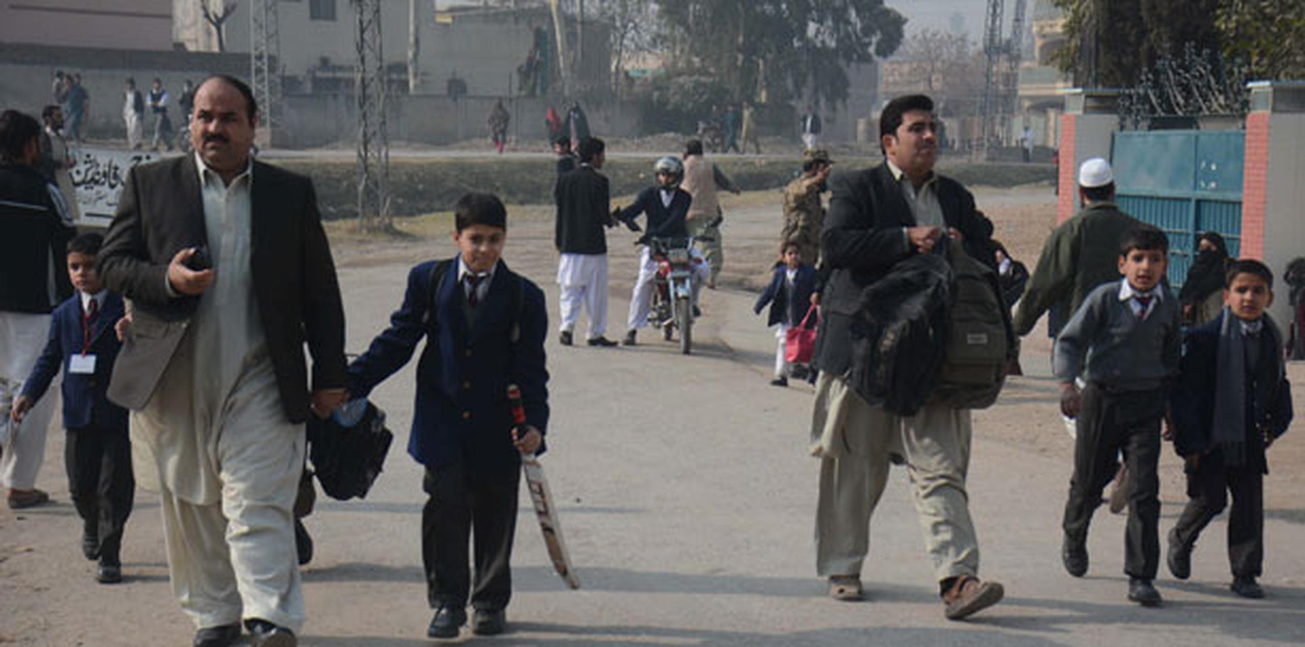 Varios alumnos acompañan a sus padres tras ser rescatados por las Fuerzas de Seguridad durante el ataque talibán contra un colegio gestionado por el Ejército en Peshawar. (Agencia EFE)