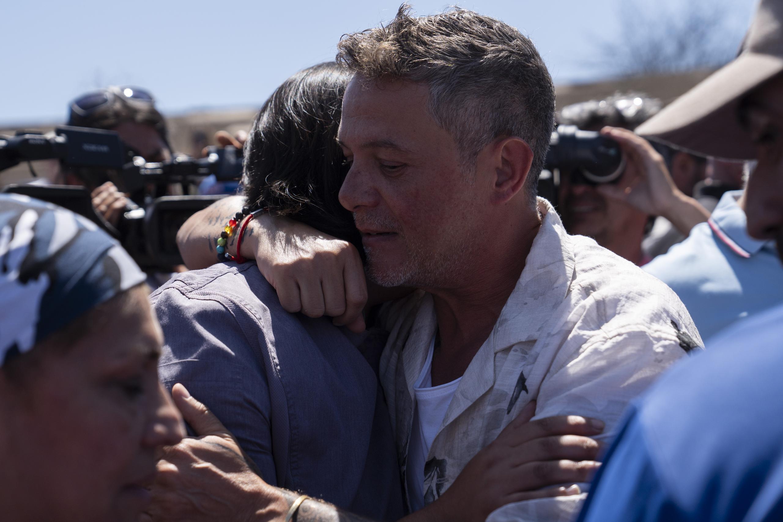 El cantante español abraza a un hombre en Villa Independencia, uno de los sectores afectados por los recientes incendios en la región.