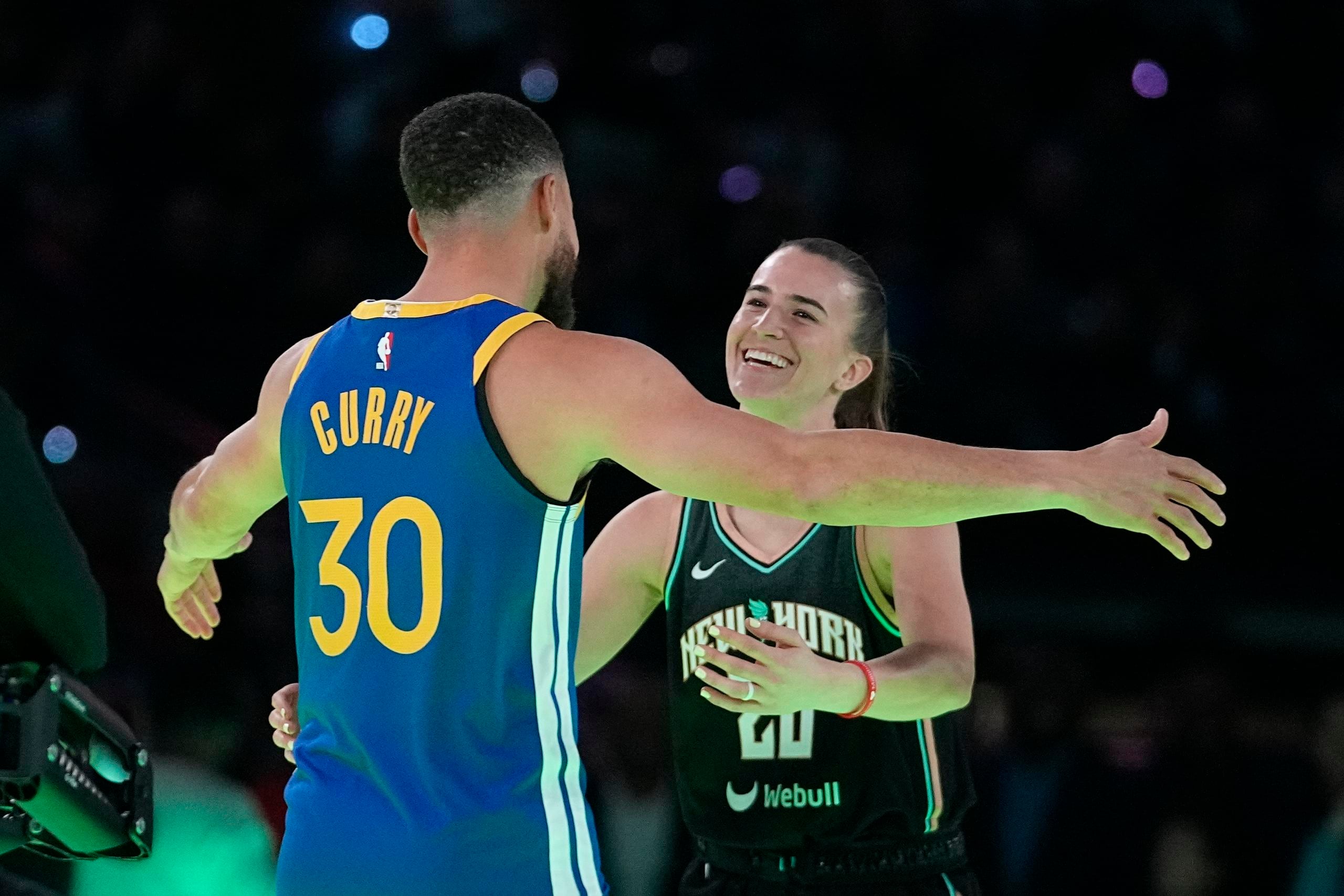 Stephen Curry, de los Warriors de Golden State, abraza a Sabrina Ionescu, del Liberty de Nueva York, tras el duelo de triples que ambos disputaron.