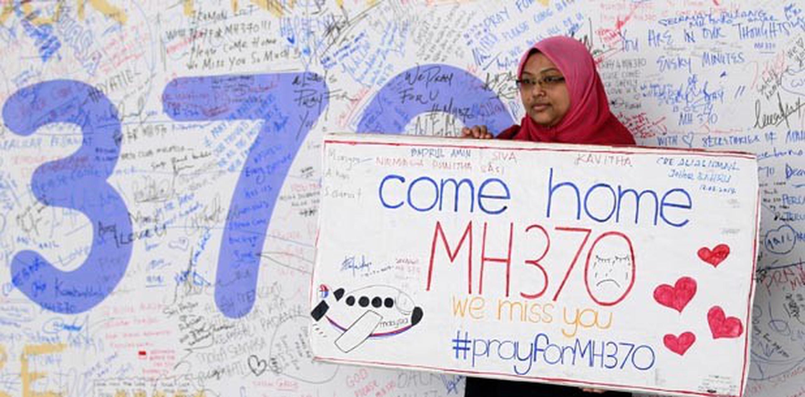 Una mujer muestra un mural con mensajes de apoyo a los pasajeros del vuelo vuelo MH370 de Malaysian Airlines desaparecido hace una semana. (EFE)