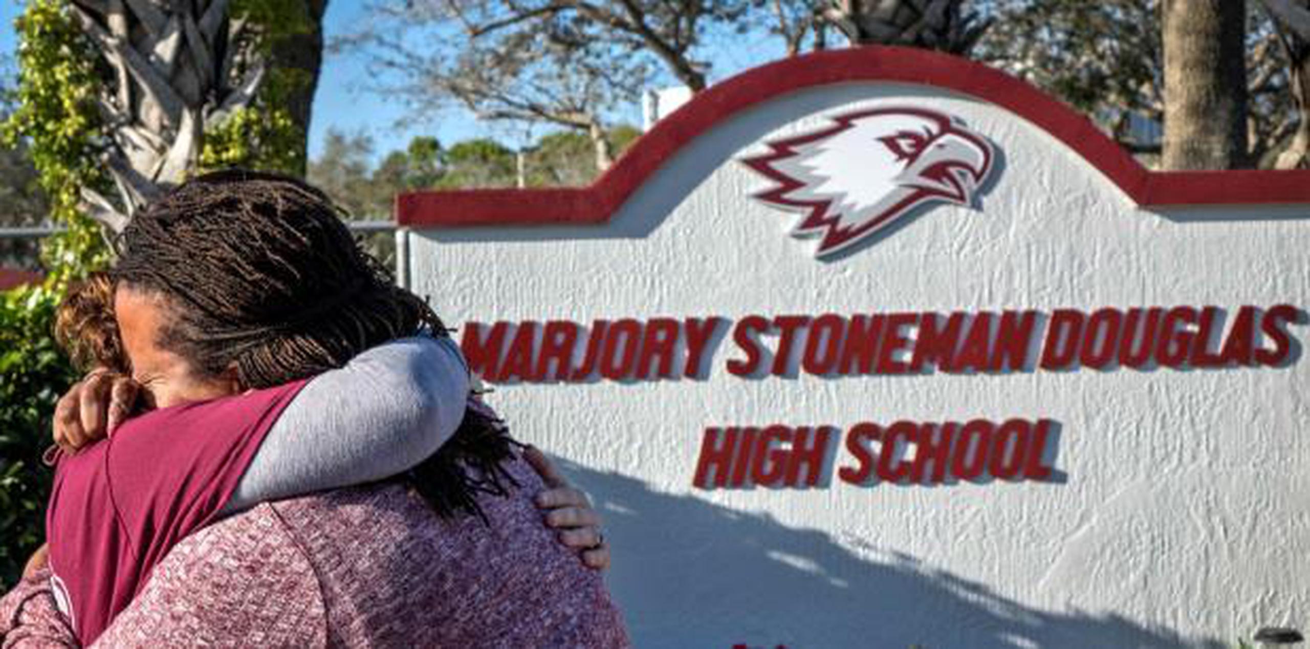 Dos mujeres se abrazan frente al monumento improvisado en conmemoración del tiroteo de hace un año en el instituto Marjory Stoneman Douglas. (EFE / Cristobal Herrera)