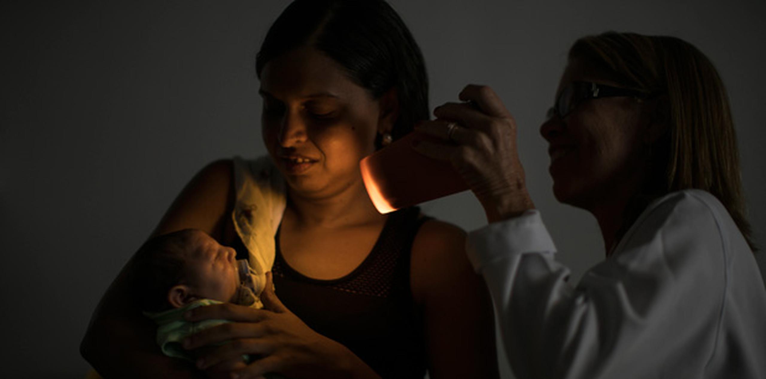 Daniele Ferreira dos Santos sostiene a su hijo Juan Pedro durante una prueba de visión. La mujer nunca fue diagnosticada con zika, pero ella culpa al virus por la malformación que padece su hijo y por las duras consecuencias que ello ha representado para su vida. (AP/Felipe Dana)
