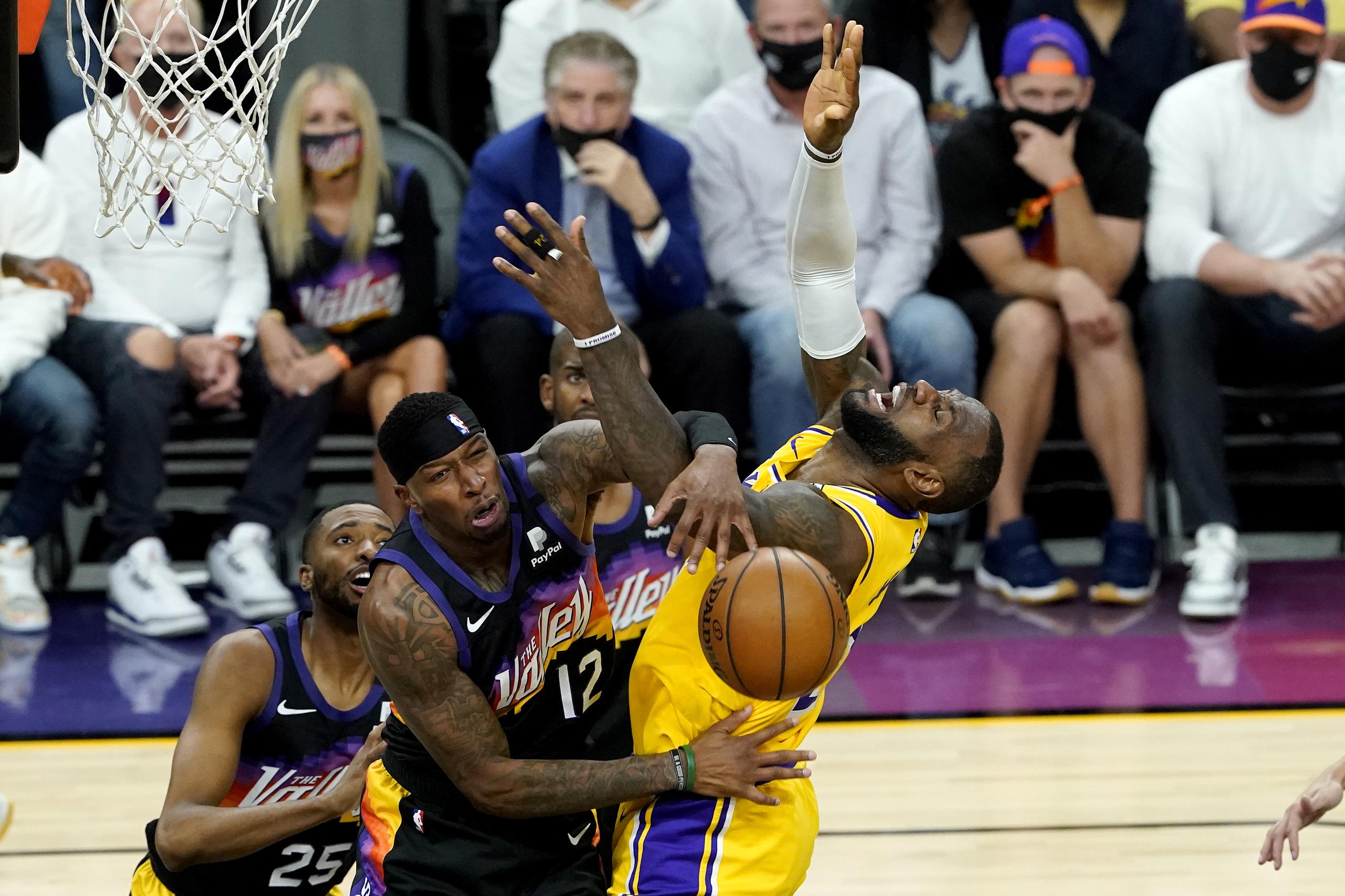 El alero de los Suns Torrey Craig (12) golpea el balón lejos del alero de los Lakers, LeBron James.