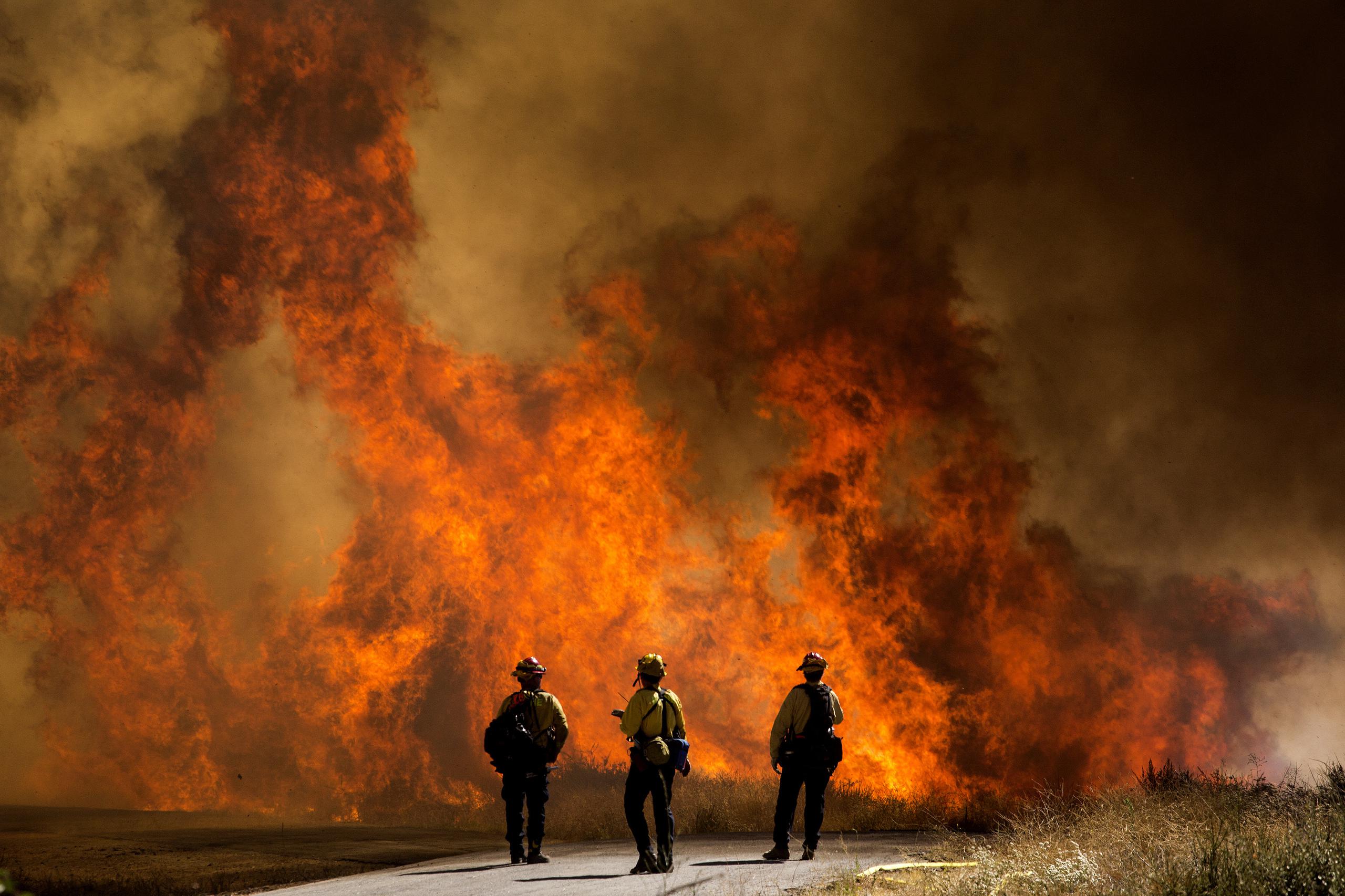 Bomberos observan las llamas del nombrado Incendio Apple en Cherry Valley, California