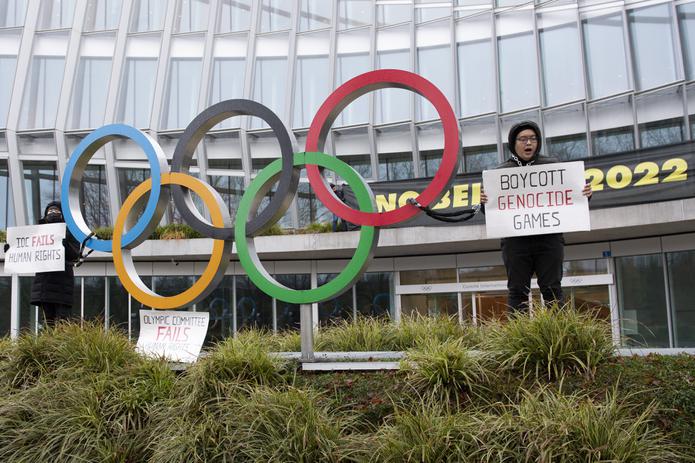 Manifestantes sostienen letreros durante una protesta contra la realización de los Juegos Olímpicos de Invierno de Pekín 2022 frente a la sede del Comité Olímpico Internacional, en Lausana, Suiza.