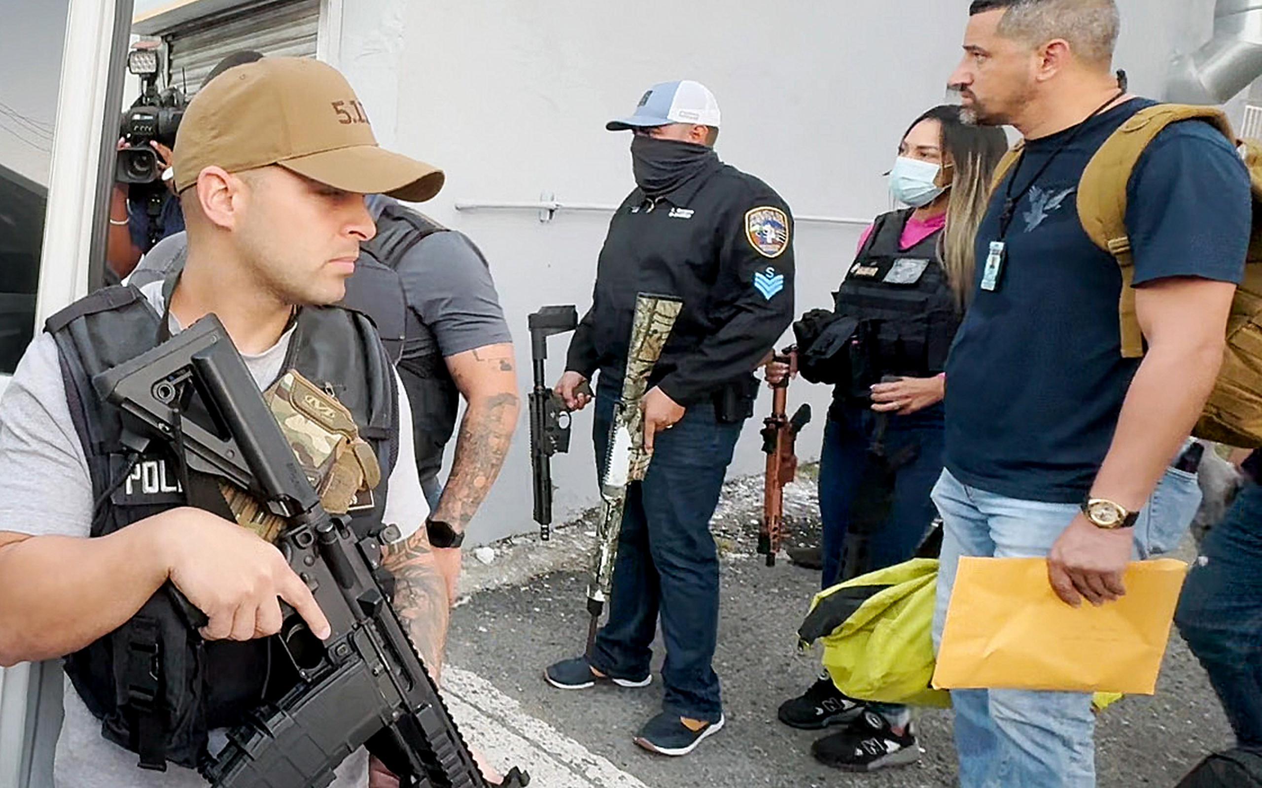 Oficiales de la Policía cargan algunos de los rifles ocupados durante un allanamiento en Santurce.
