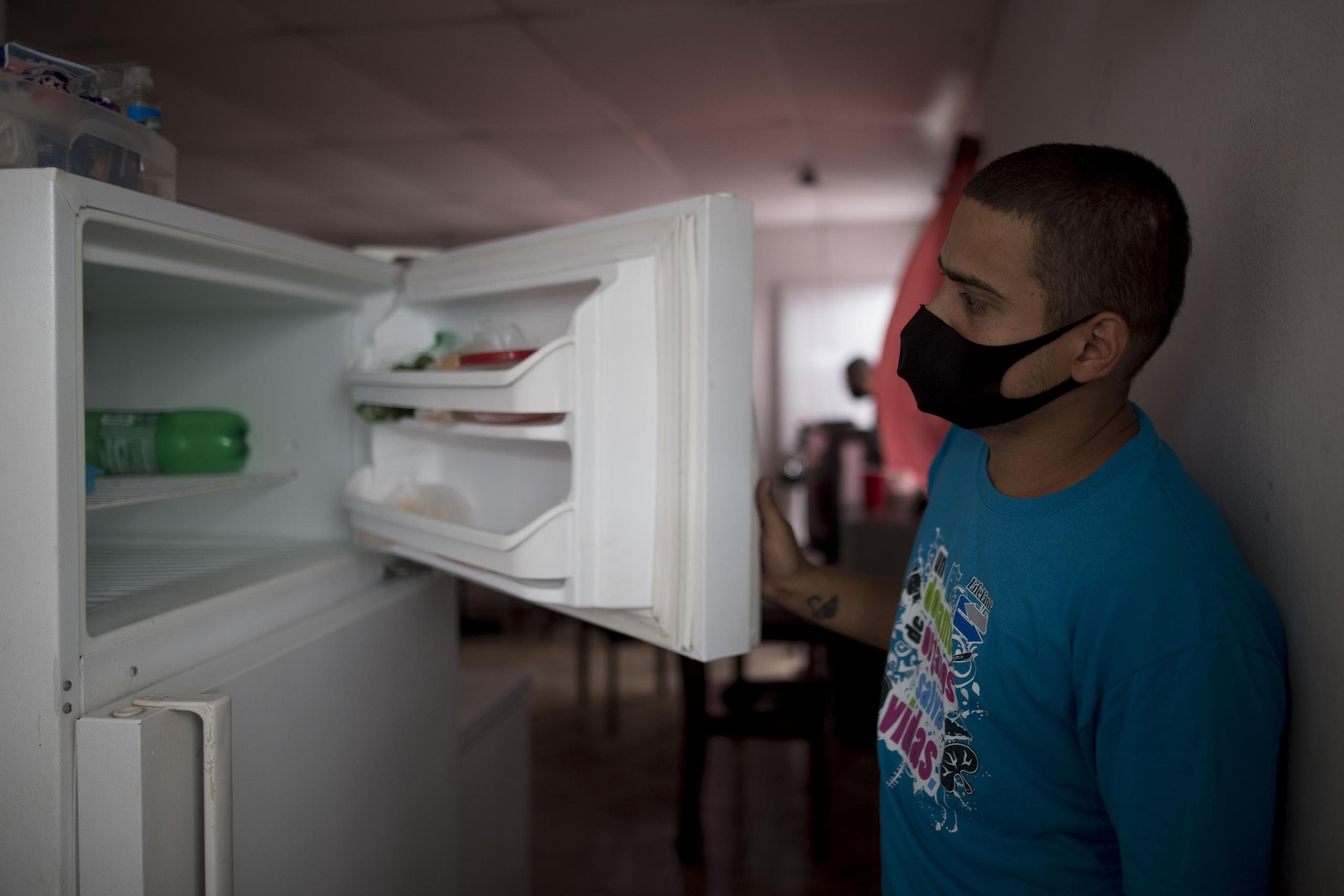 Ángel Ruiz muestra su congelador vacío en su casa, donde él y su esposa, Ivelisse Ríos, viven con sus dos hijos en San Juan