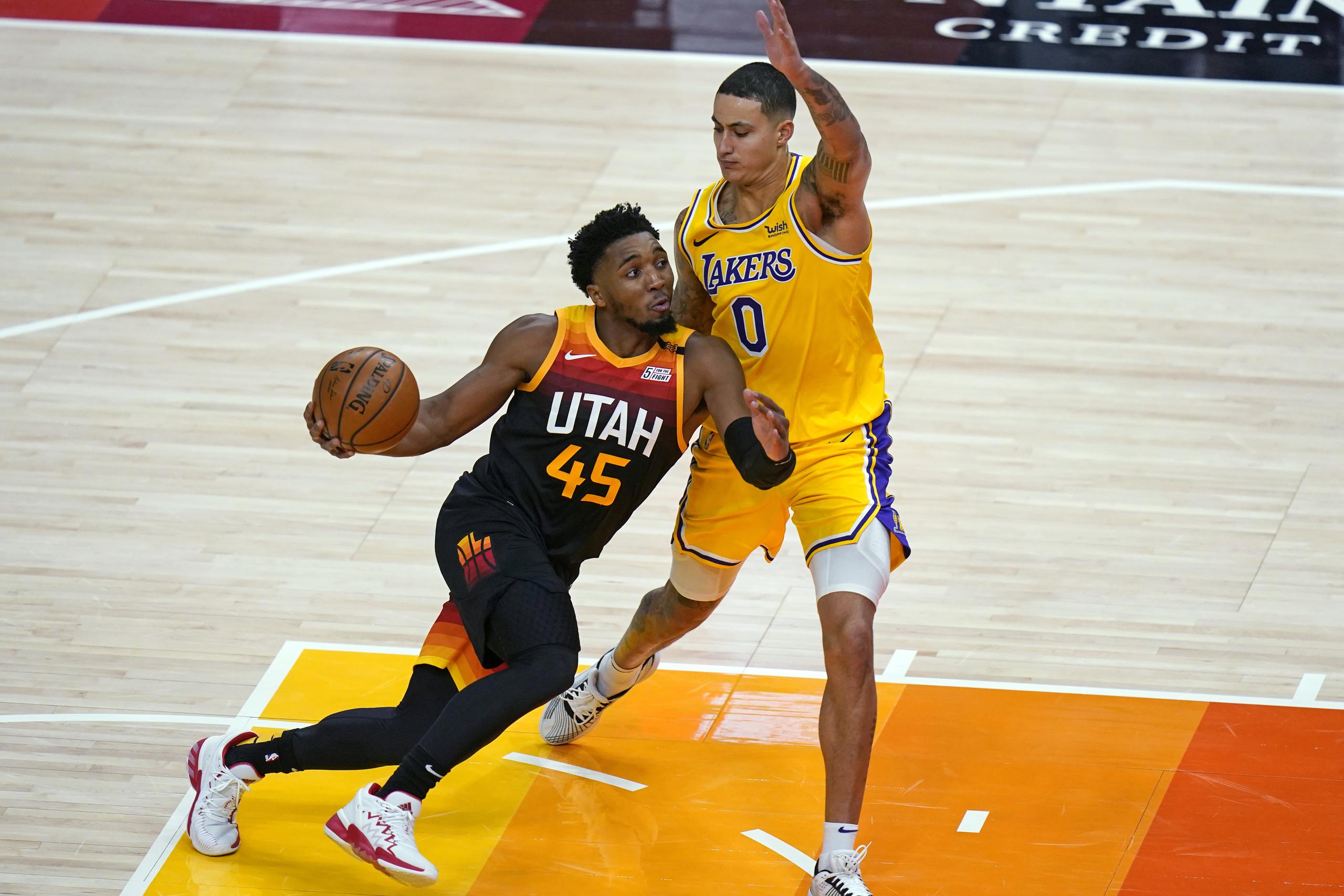 Donovan Mitchell del Jazz de Utah impulsa contra el alero de los Lakers de Los Ángeles Kyle Kuzma.
