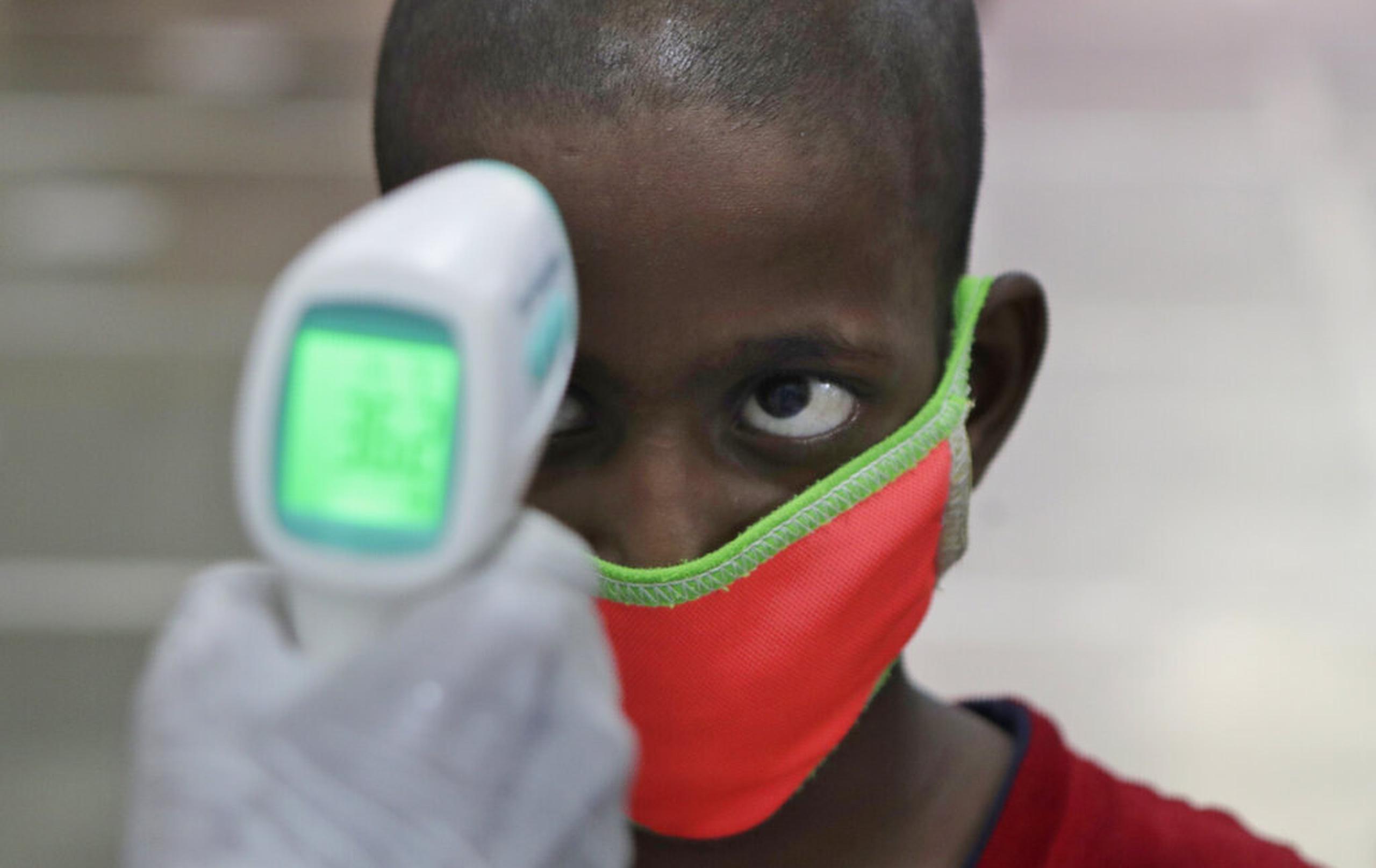 Un trabajador sanitario verifica la temperatura corporal de un niño en Mumbai, India.