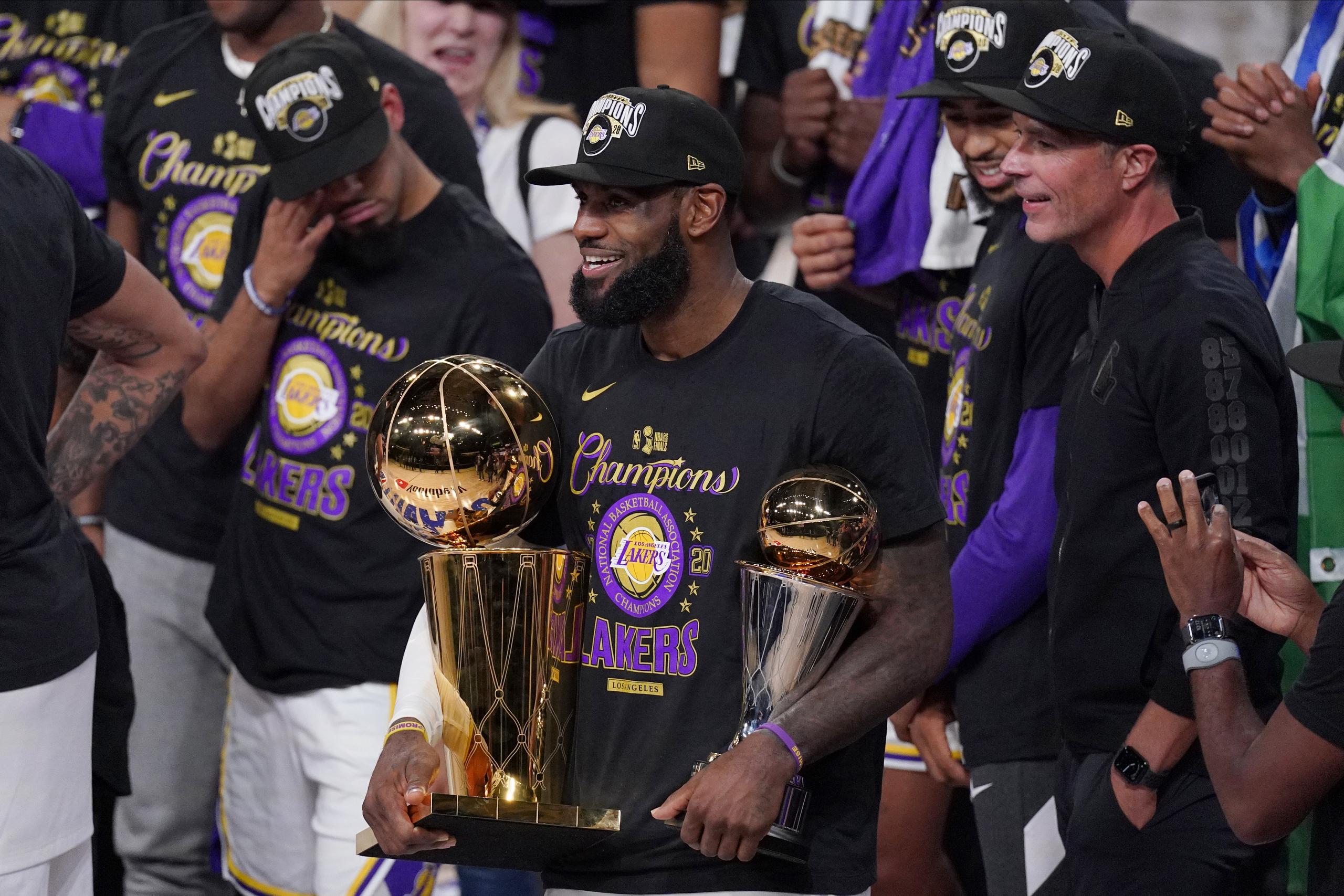 Junto a sus compañeros, LeBron James, de los Lakers, sostiene su cuarto trofeo de campeón de la NBA y su cuarto premio al Jugador Más Valioso de la Final de la NBA.