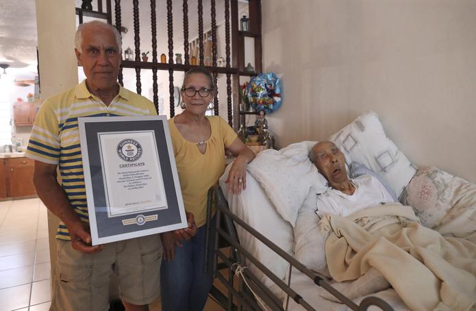 Tirsa y Emilio Flores posan junto a su padre, Emilio Flores Márquez, quien ostentaba el récord Guinness como el hombre más viejo del mundo.