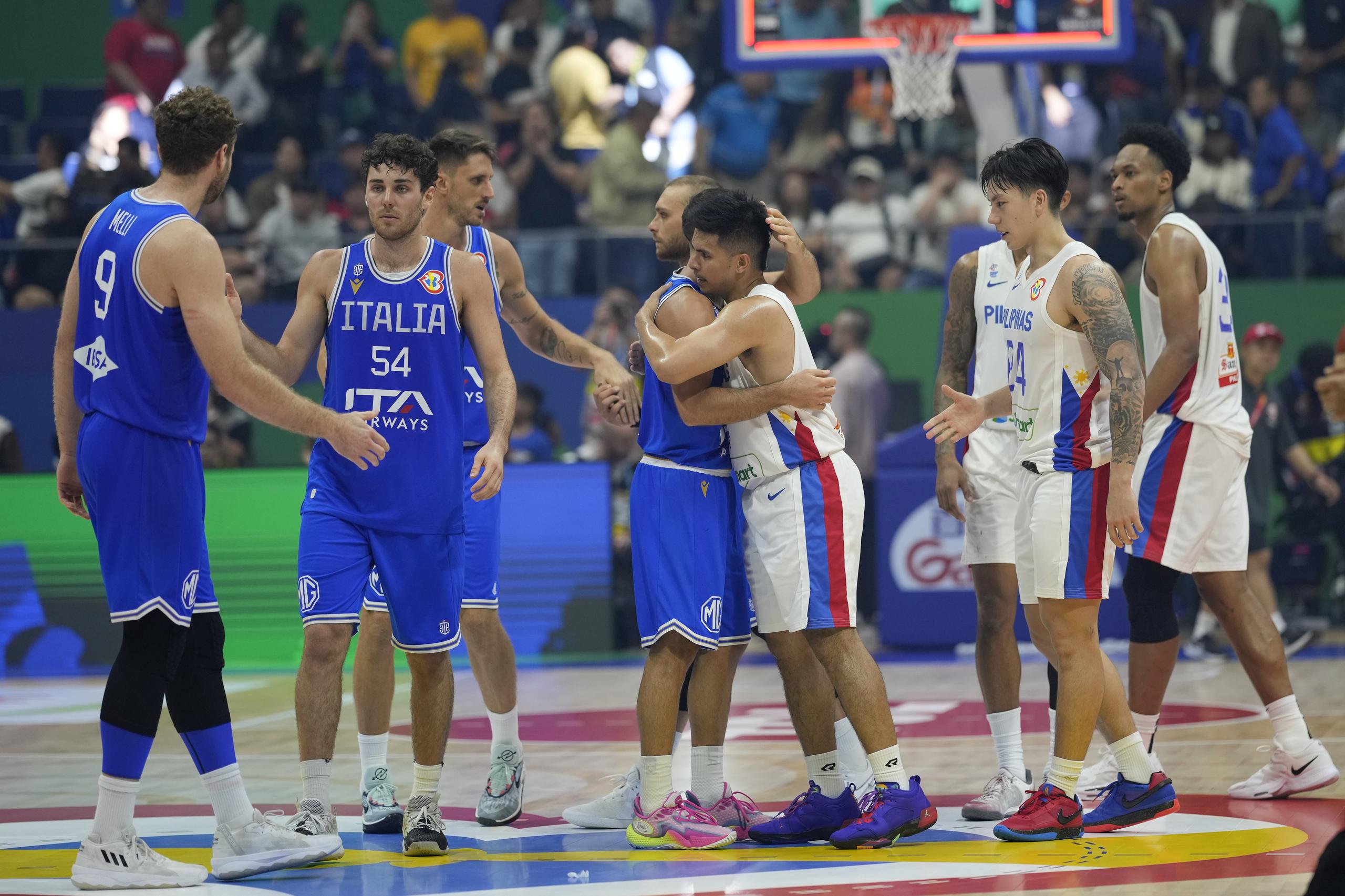 El defensa de Italia, Marco Spissu (0), y Kiefer Ravena (4), de Filipinas, se abraza luego de un juego en la fase preliminar. 
