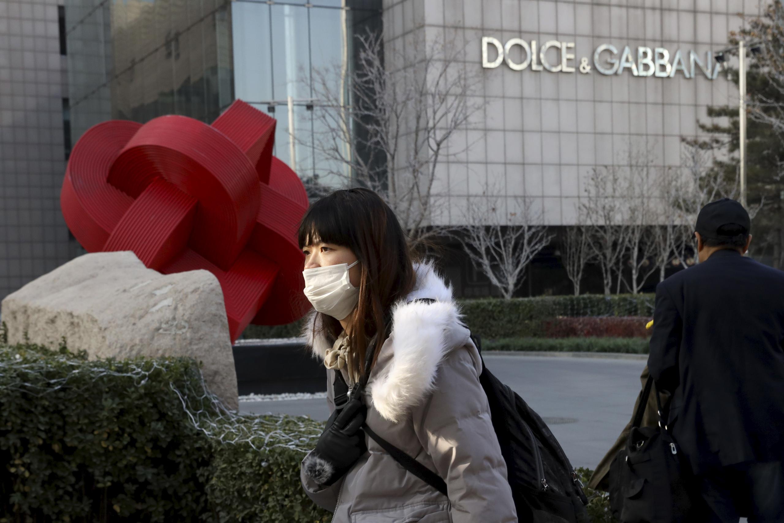Una mujer caminando frente a una tienda de Dolce&Gabbana en Beijing, China.