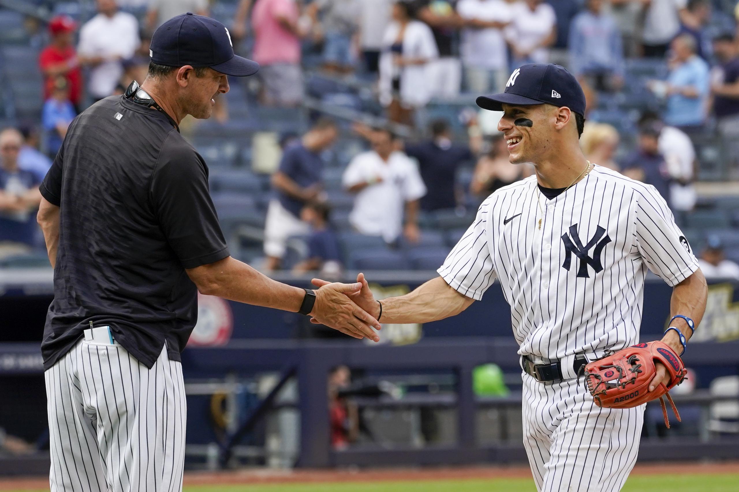 El dirigente de los Yankees de Nueva York, Aaron Boone, a la izquierda, felicita a Andrew Velázquez luego de la victoria del equipo el sábado en el Yankee Stadium.