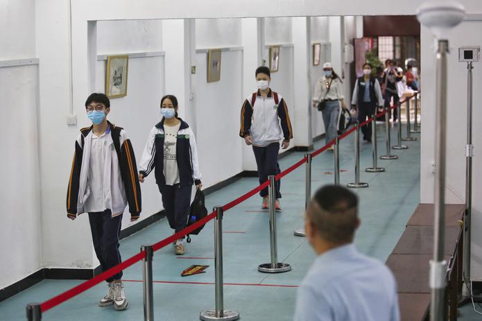 Estudiantes con mascarillas y a cierta distancia unos de otros para evitar la propagación del coronavirus llegan a una secundaria en la ciudad de Wuhan, provincia de Hubei, en el centro de China