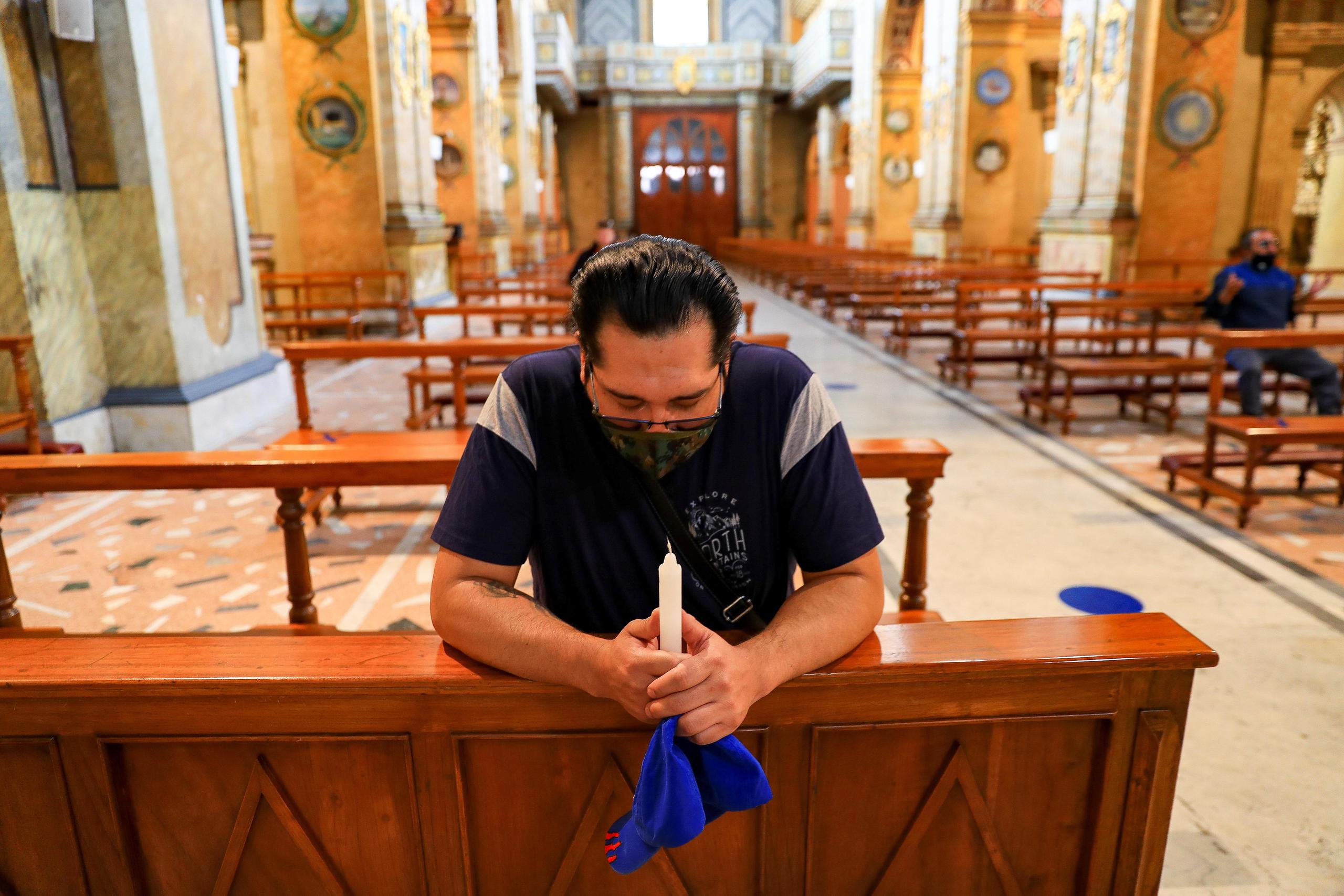 Un ecuatoriano con mascarilla reza este jueves, en la iglesia de Santo Domingo, en Quito (Ecuador).