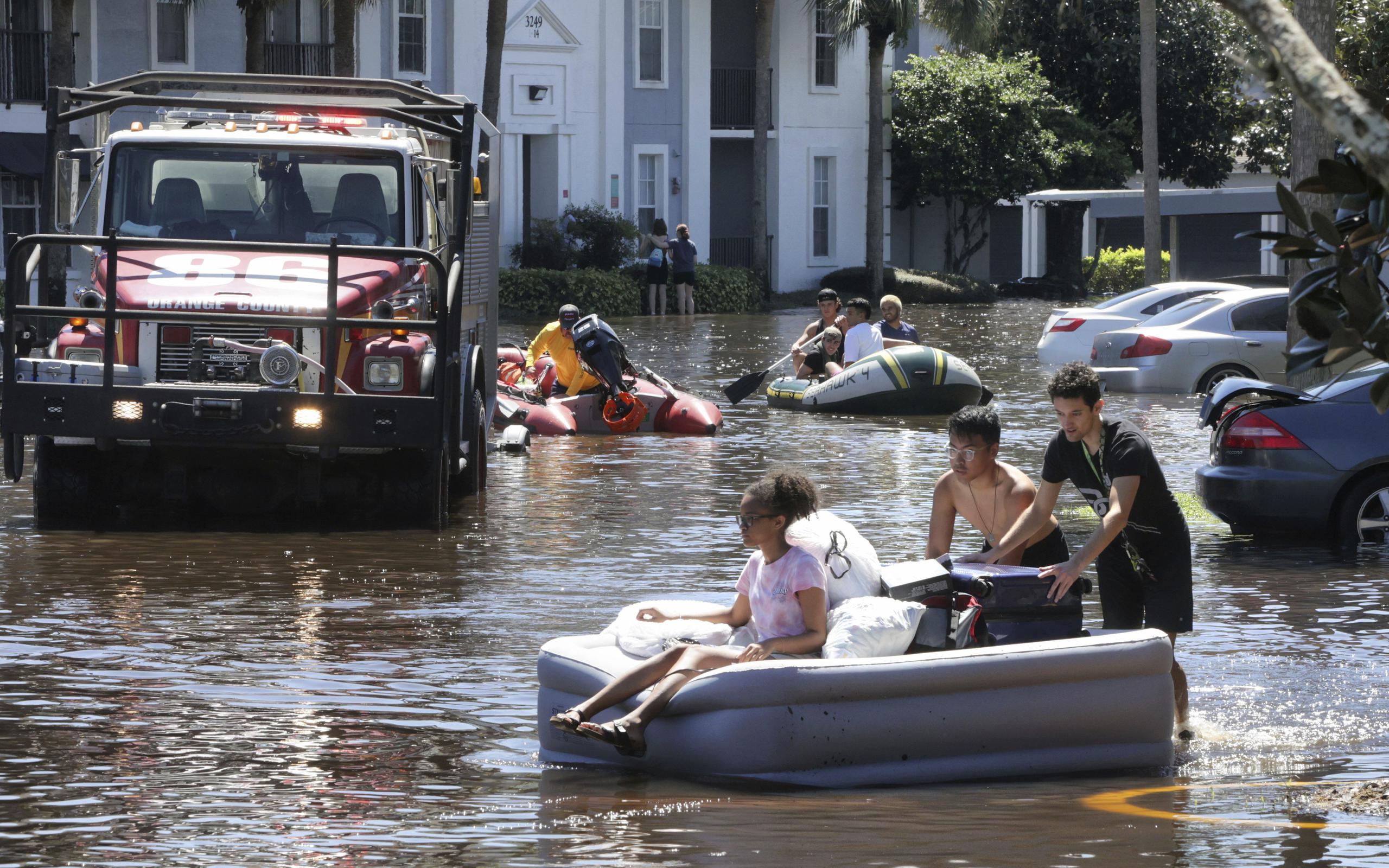 Estudiantes de la Universidad Central de Florida usan un colchón inflable para evacuar un complejo de apartamentos que quedó inundado por la lluvia del huracán Ian.
