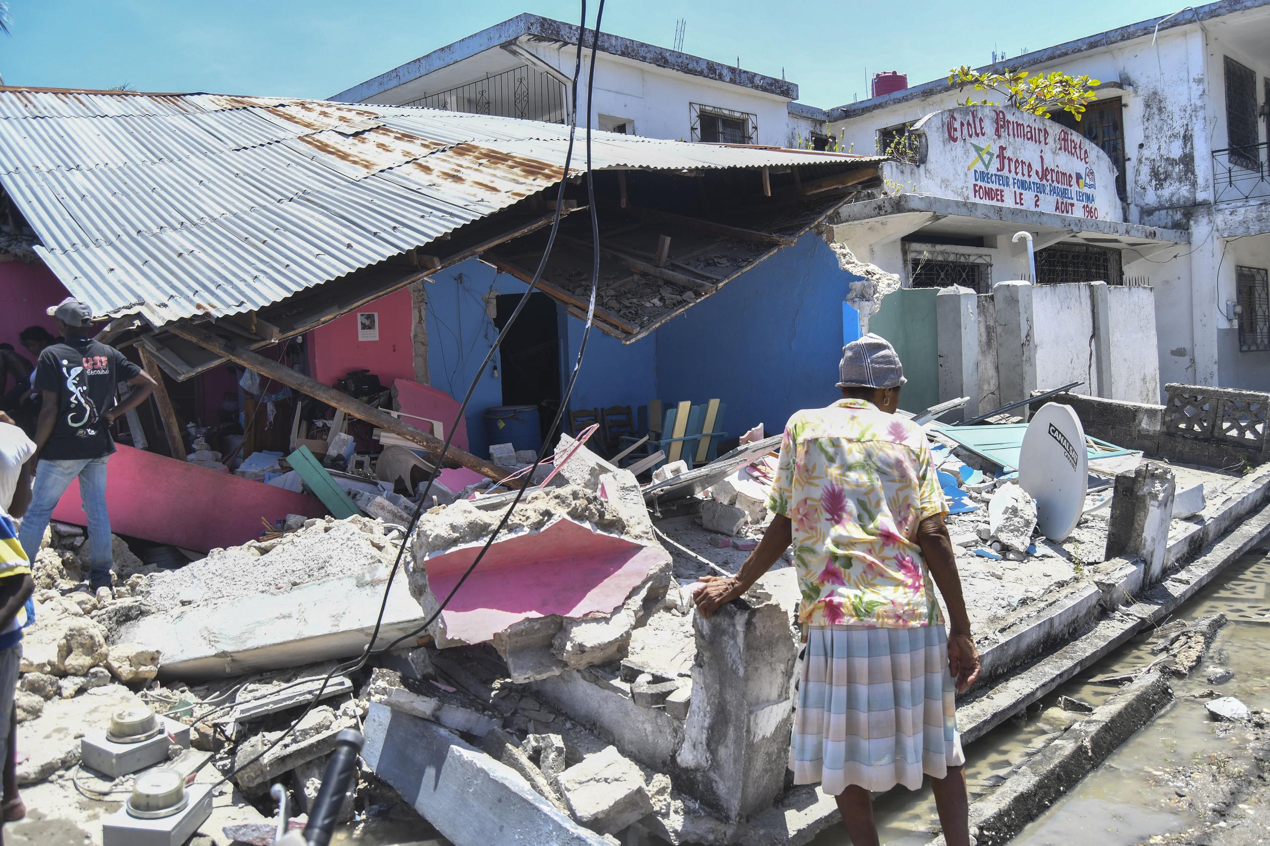 Una mujer se para frente a una casa destruida después de un terremoto en Les Cayes, Haití.