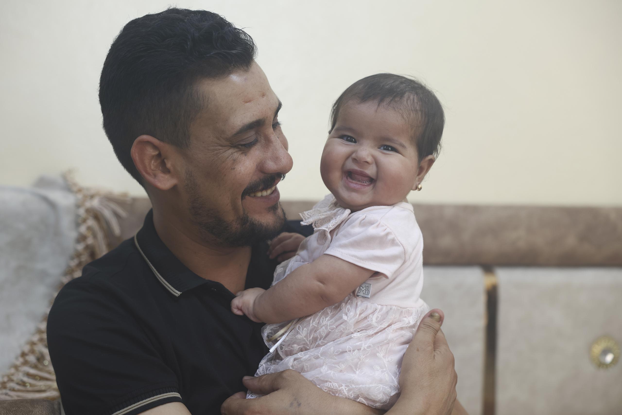 Khalil al-Sawadi juega con su sonriente hija adoptiva, Afraa.