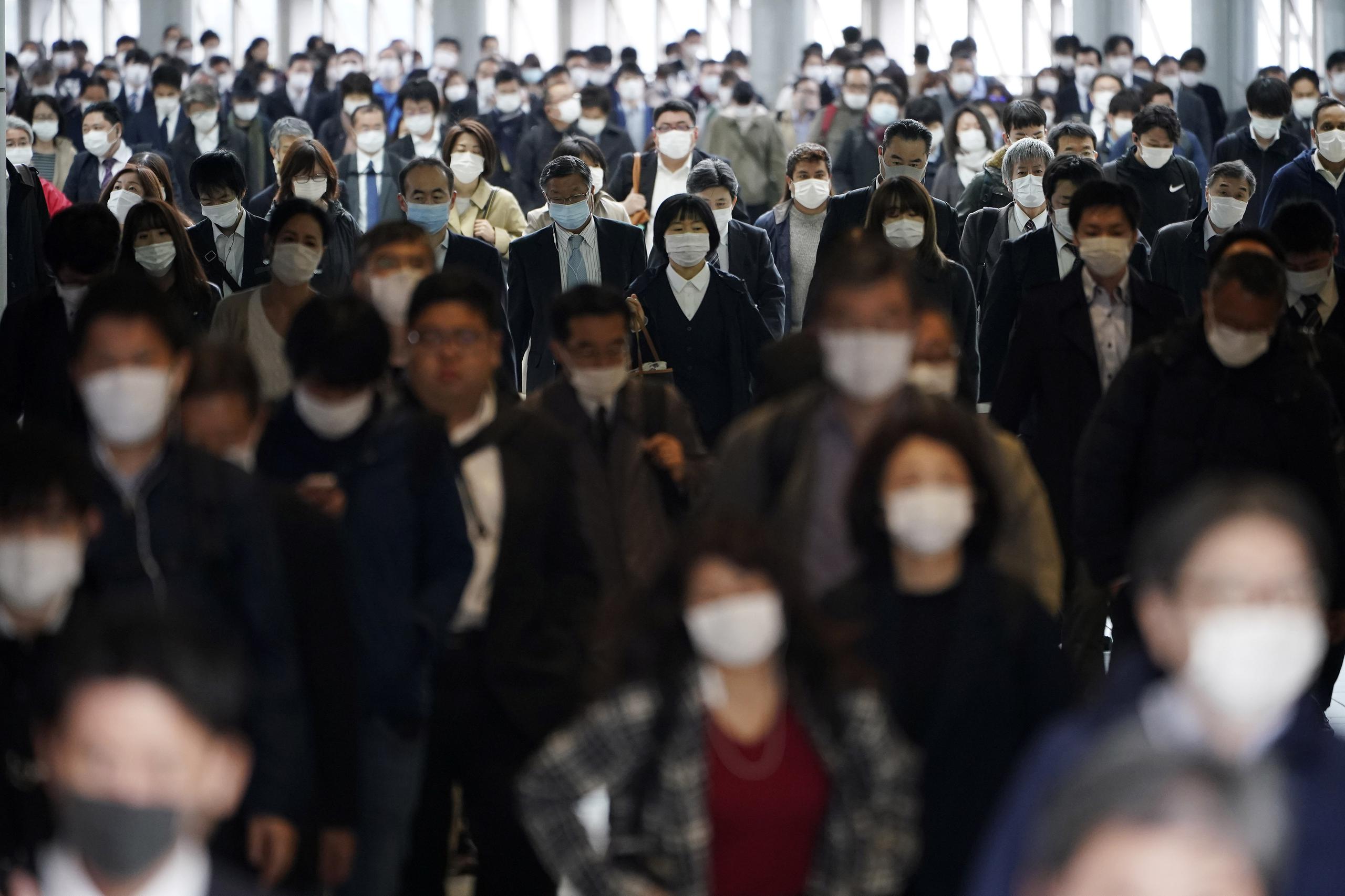 Pasajeros en una estadio del metro de Tokio caminan en su mayoría protegidos con mascarillas.