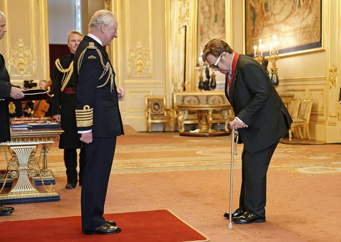 Sir Elton John, a la derecha, es nombrado miembro de la Orden de los Compañeros de Honor por el príncipe Carlos en una ceremonia en el Castillo de Windsor, en Windsor, Inglaterra, el miércoles 10 de noviembre de 2021. (Aaron Chown/PA via AP)