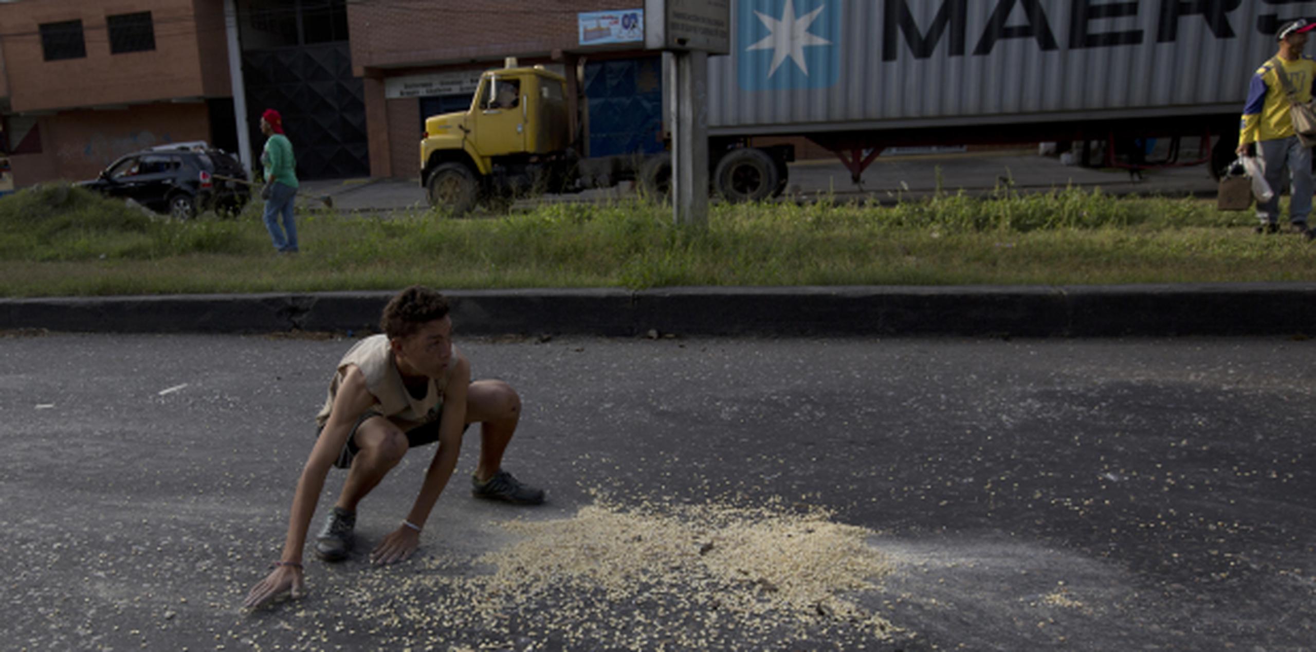 A las afueras del Puerto Cabello este jovencito recogía de la carretera unos pocos granos de maíz que se habían caído de un furgón. (AP)