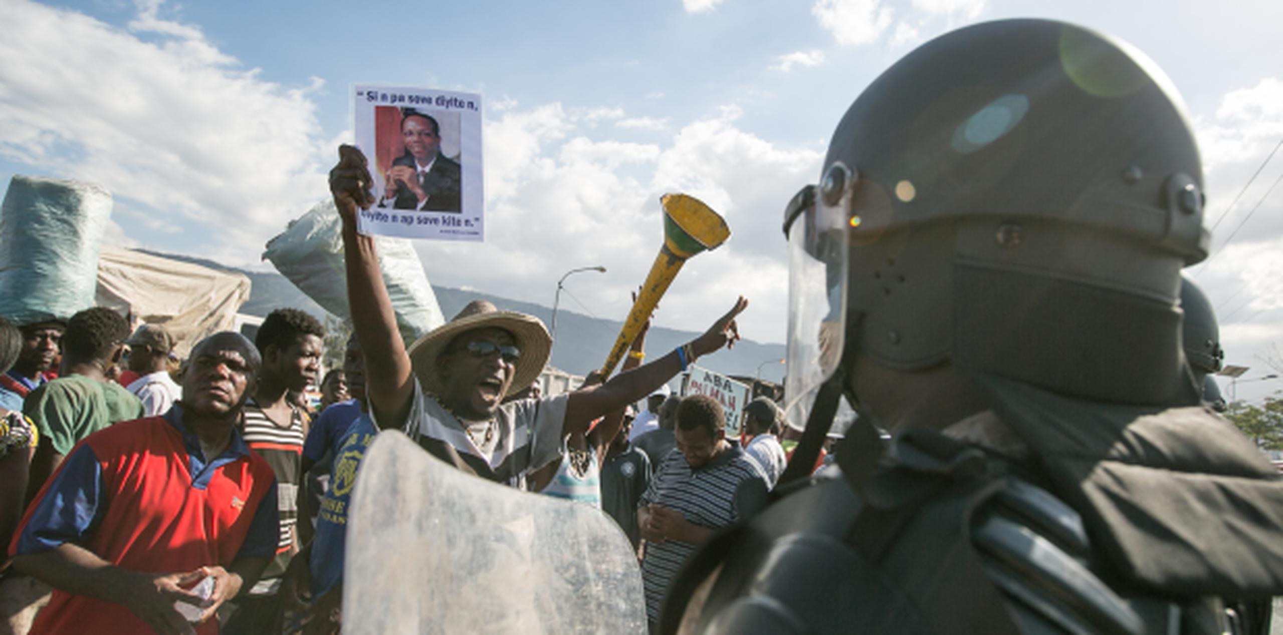 La Policía vigila una protesta ciudadana en momentos en que se elegía en el parlamento haitiano un presidente interino para la vecina república. (EFE)