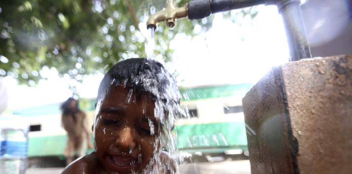 Un niño se ducha en la calle para tratar de aplacar el calor. Entre las medidas ante las altas temperaturas se han suspendido las clases y el trabajo en el gobierno. (EFE)