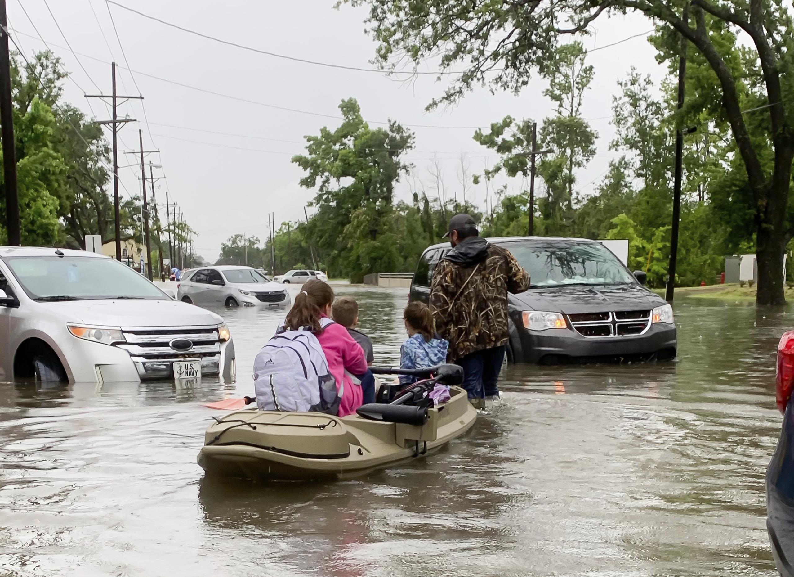 Padres usan kayaks para recoger a estudiantes de las escuelas después de que cayeran fuertes lluvias en Lake Charles, Luisiana.