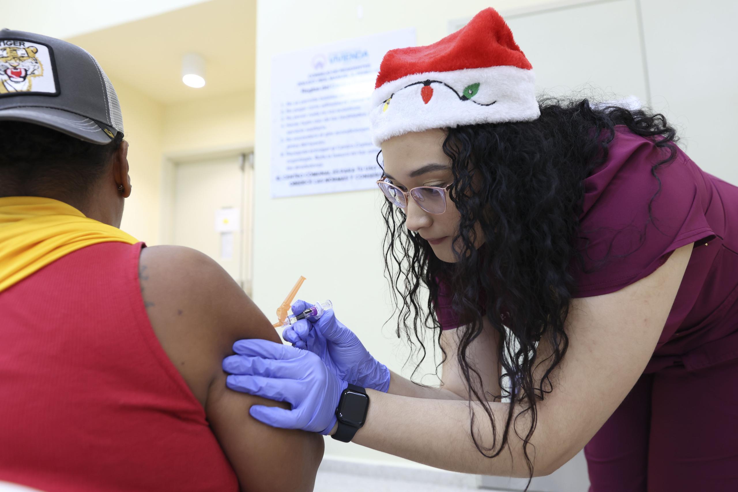 Paola del Mar Díaz, estudiante de enfermería, administra una vacuna a una residente del residencial Manuel A.  Pérez.