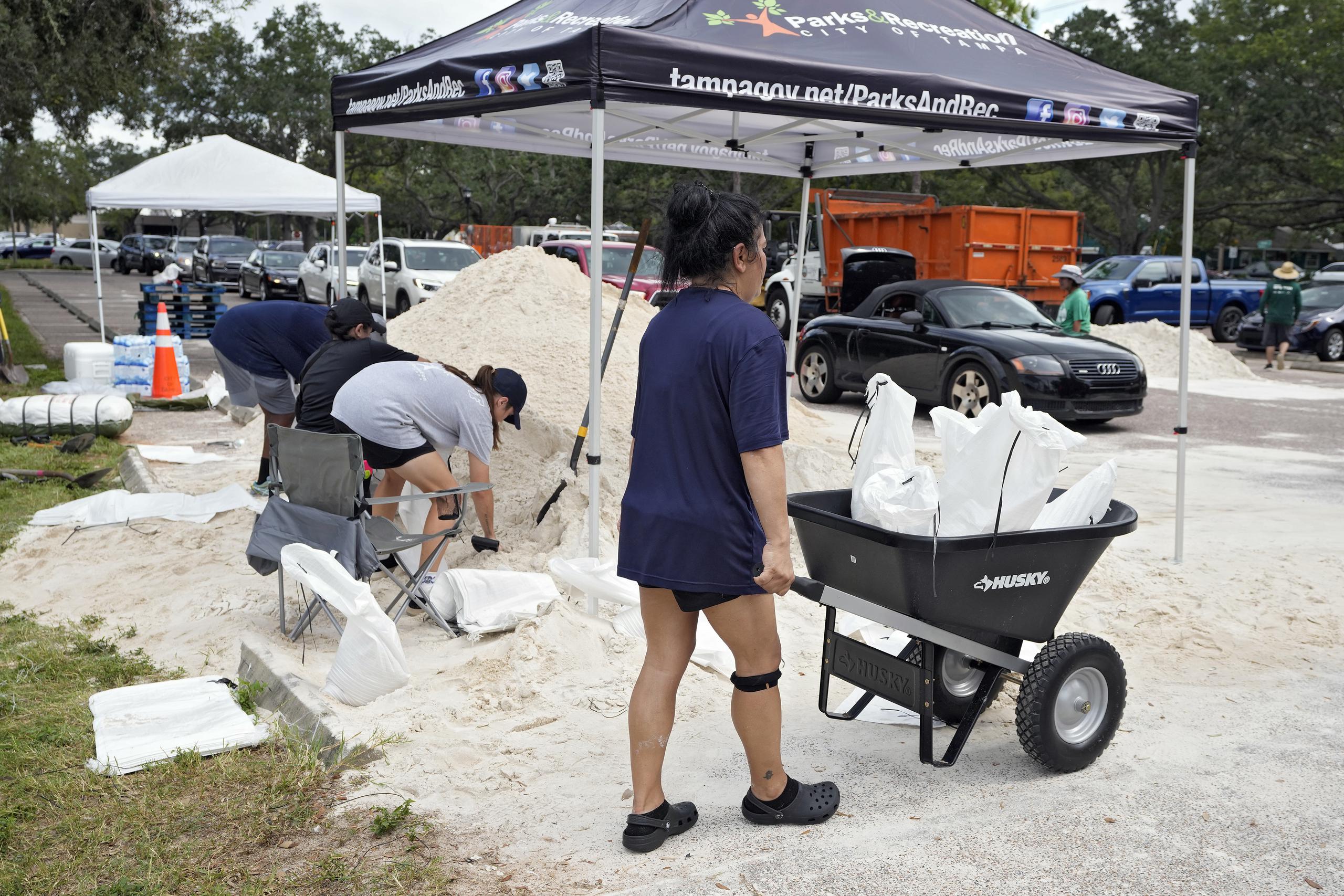 Elementos del Departamento de Parques y Recreación de Tampa, Florida, entregan costales de arena a los residentes, el lunes 28 de agosto de 2023, en Tampa. (AP Foto/Chris O'Meara)