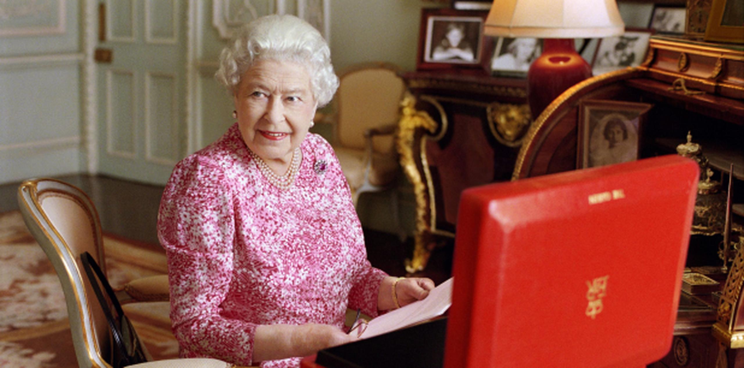 El palacio de Buckingham cedió esta foto reciente de isabel II en su despacho, con la maleta roja en la que recibe documentos importantes. (EFE/Mary McCartney)