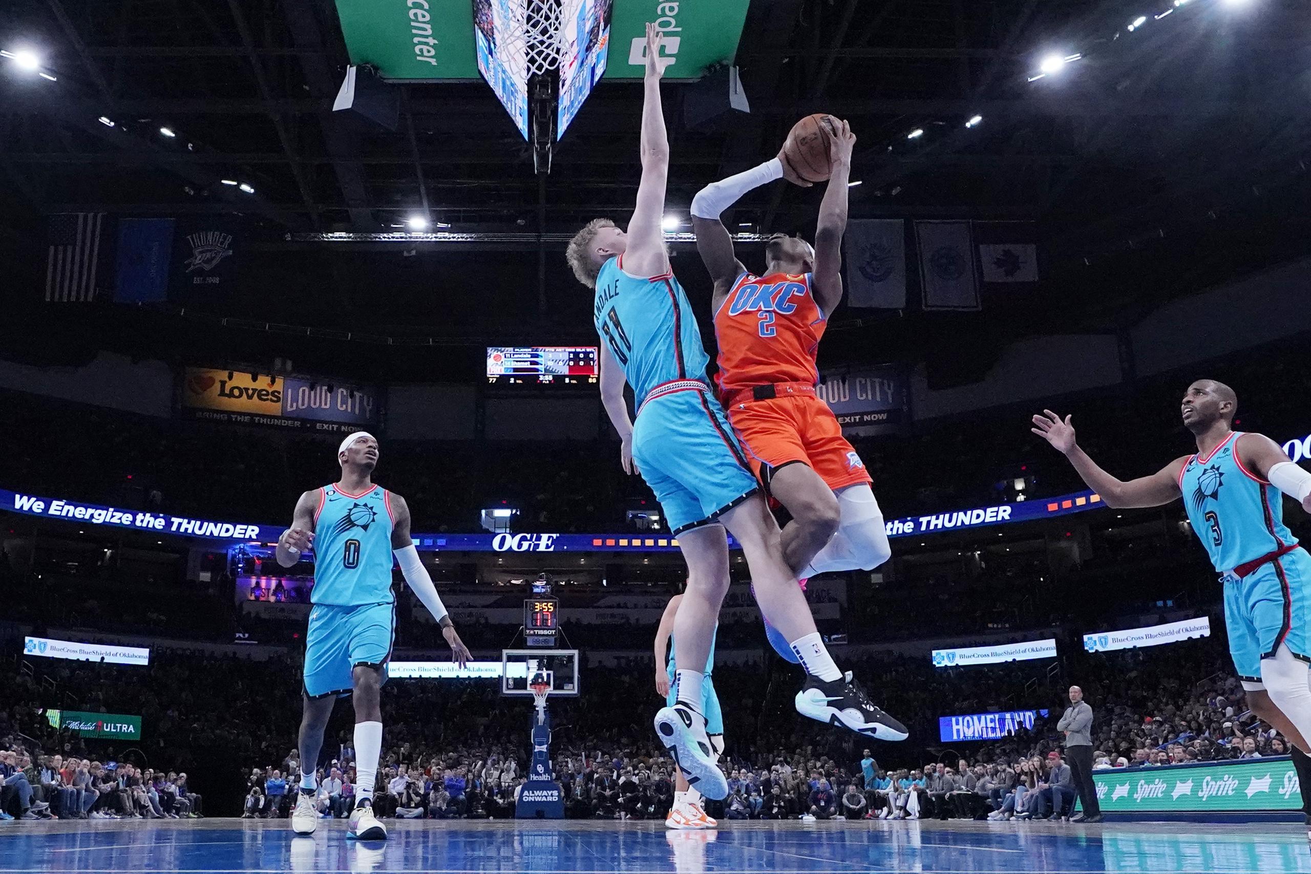 Shai Gilgeous-Alexander (2), del Thunder de Oklahoma City, dispara sobre la presión del pívot de los Suns de Phoenix, Jock Landale (11), en la segunda mitad del juego de baloncesto de la NBA, el domingo 19 de marzo de 2023, en Oklahoma City. (AP Foto/Sue Ogrocki)