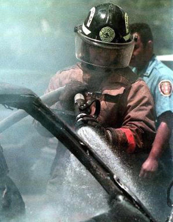 Un bombero apaga un auto incendiado. (Archivo)