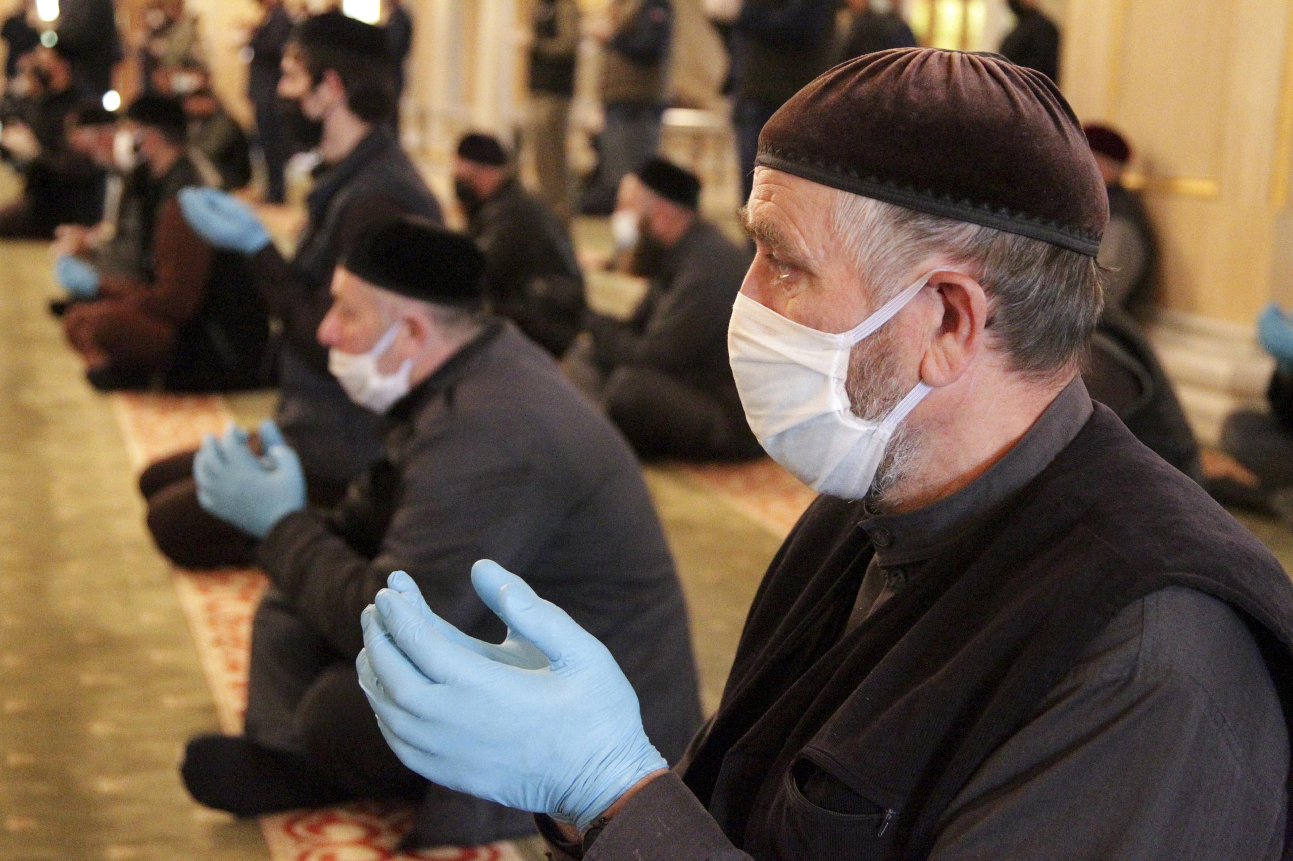 Musulmanes oran con guantes y mascarillas en Rusia.