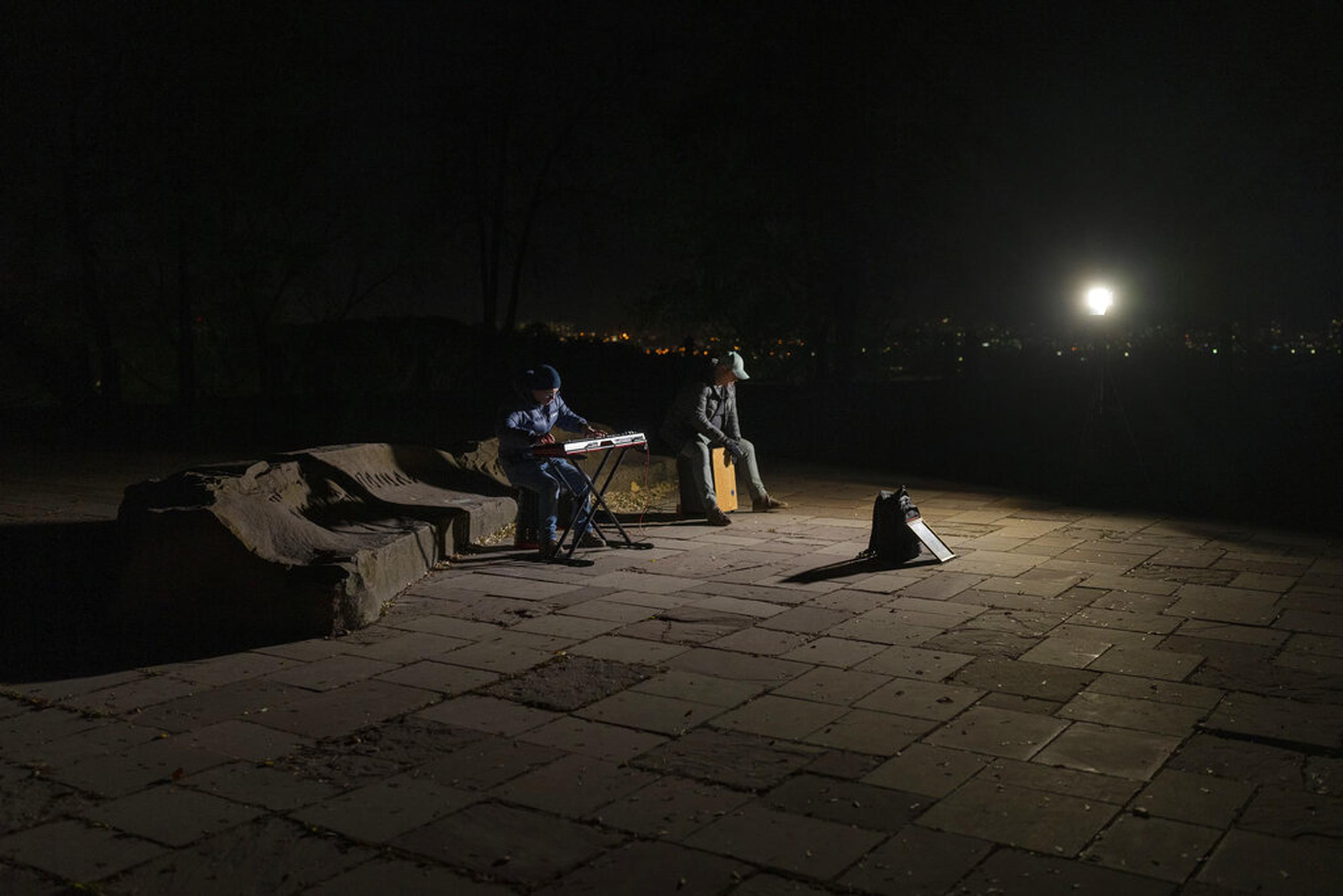 Músicos callejeros tocan instrumentos en una plaza sin luz eléctrica en Kiev, Ucrania, el 18 de octubre de 2022.