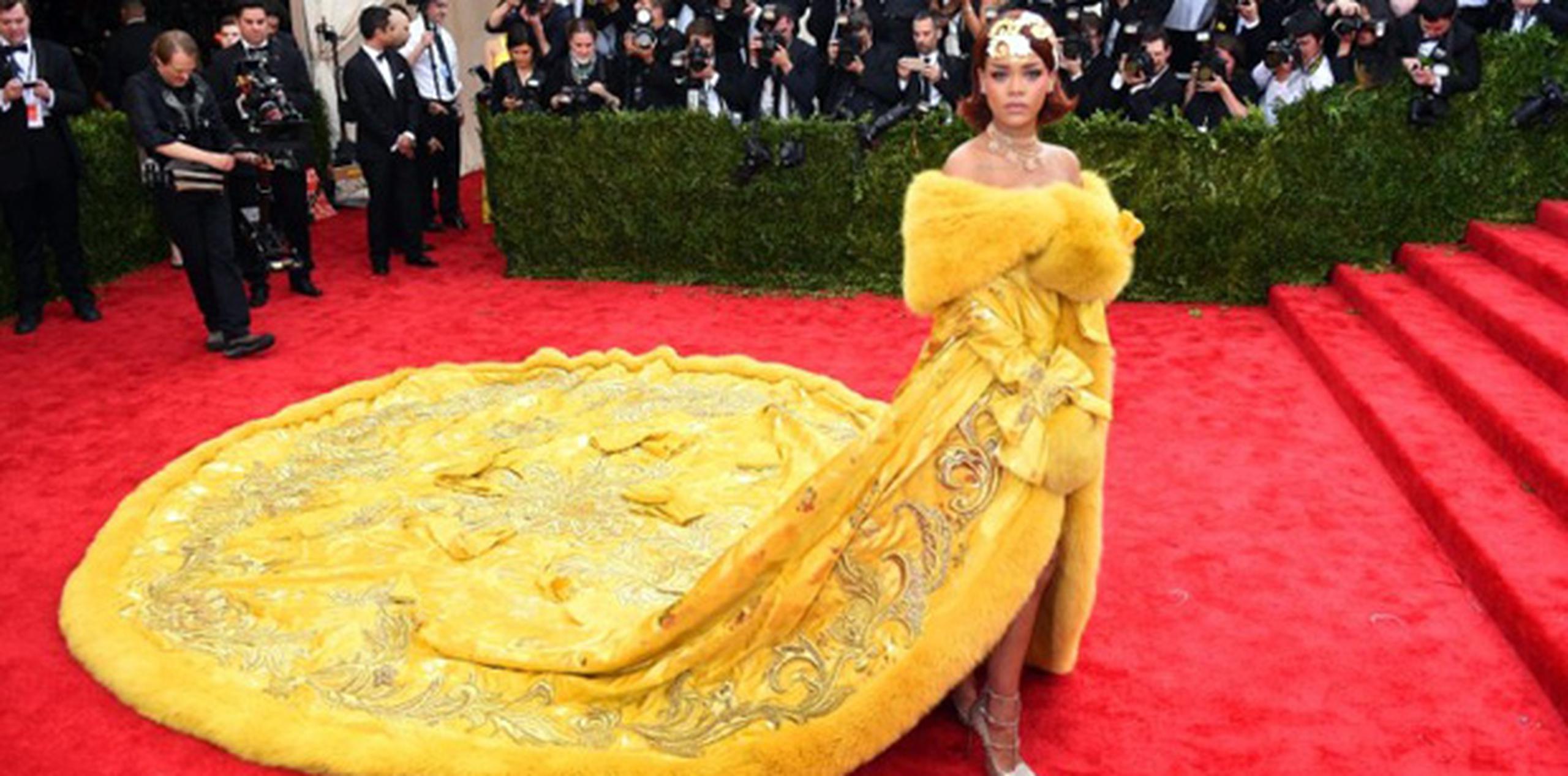 Rihanna consiguió acaparar la atención y conquistar la alfombra roja de la Gala del Met cuando apareció ataviada con una gran capa amarilla con ribetes de piel y bordados florales dorados, y una cola tan larga que requería tres asistentes. (AFP)