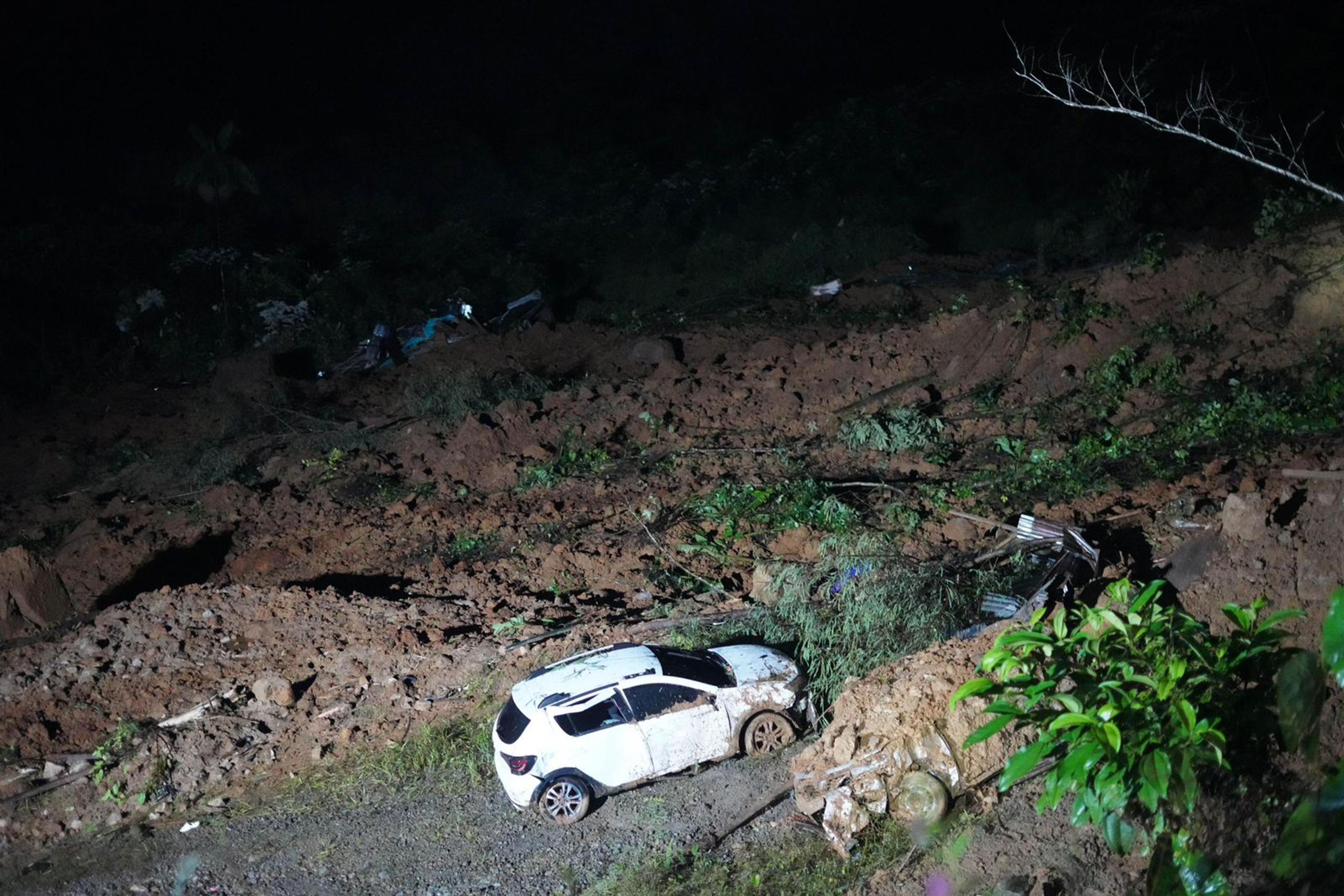 Restos de vehículos y lodo son observados en el lugar donde ocurrió un derrumbe el viernes en las inmediaciones del municipio de Carmen de Atrato, departamento del Chocó (Colombia).