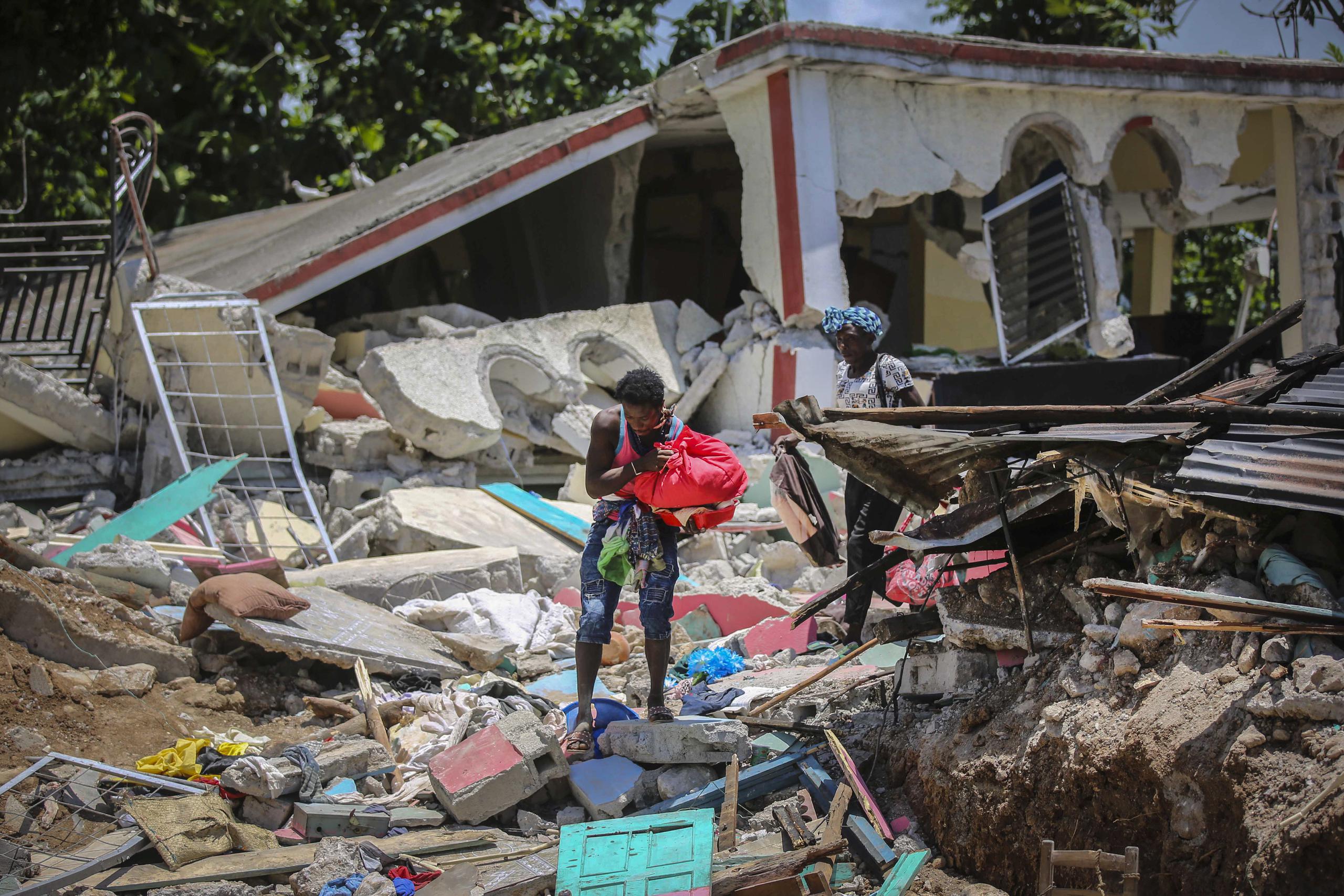 Unas mujeres recuperan sus pertenencias de sus casas destrozadas el domingo 15 de agosto de 2021, en Les Cayes, Haití, luego de un sismo de magnitud 7.2.