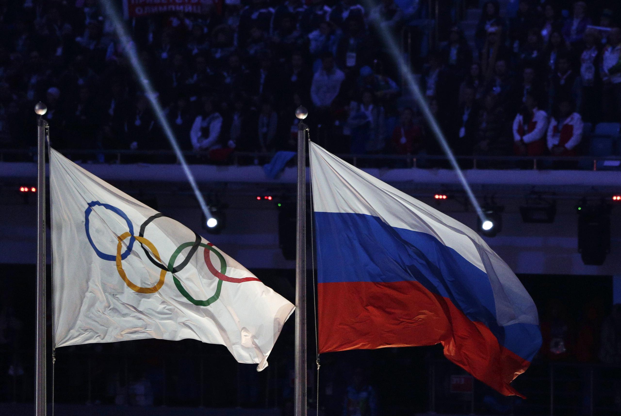 La bandera de Rusia (a la derecha) flamea junto a la de los Juegos Olímpicos durante la ceremonia de clausura de los Juegos de Invierno, en Sochi, el 23 de febrero de 2014.