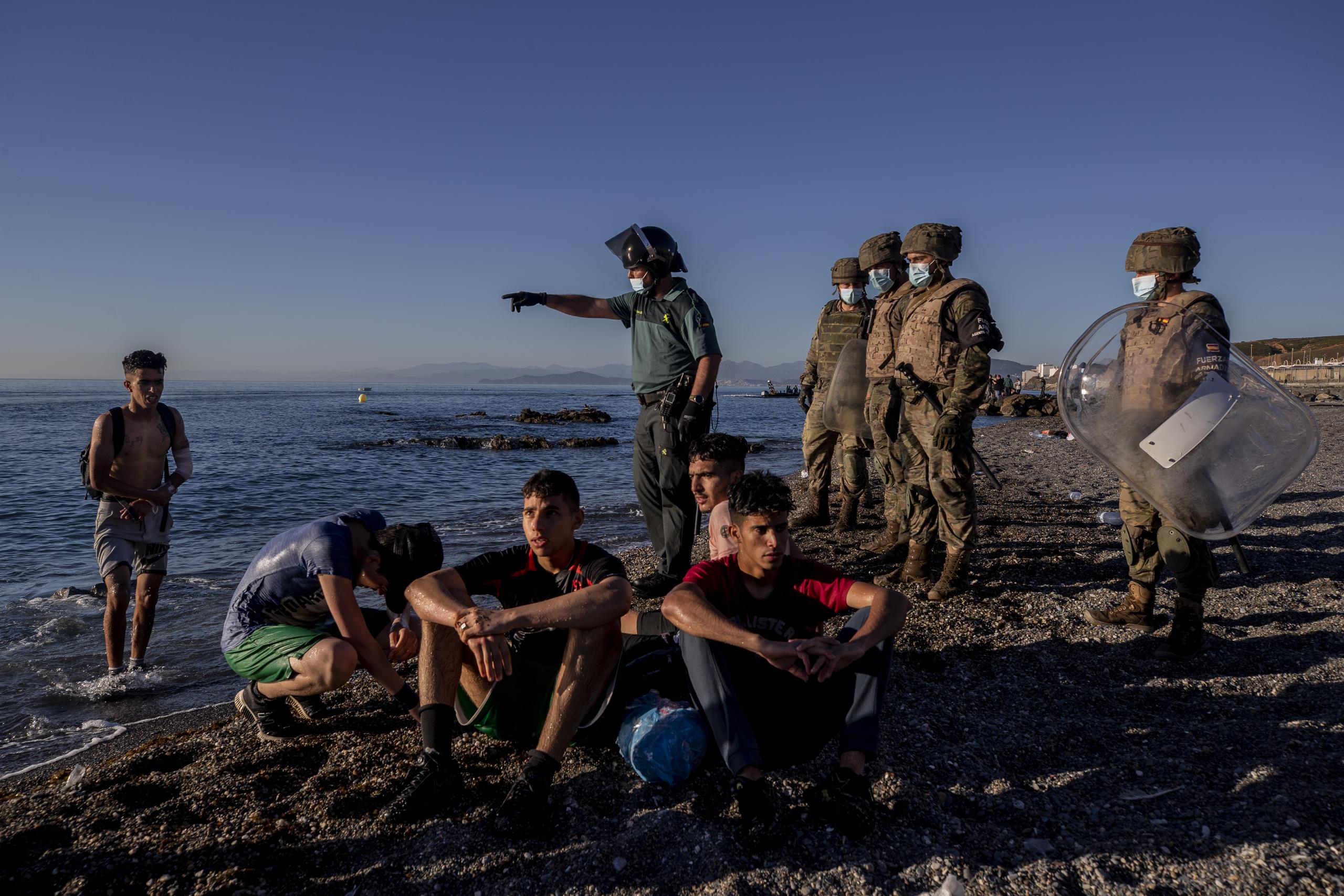 La foto de archivo del 19 de mayo de 2021 muestra a migrantes rodeados por agentes de policía españoles en una playa en el enclave español de Ceuta, cerca de la frontera con Marruecos. (AP Foto/Bernat Armangue, File)