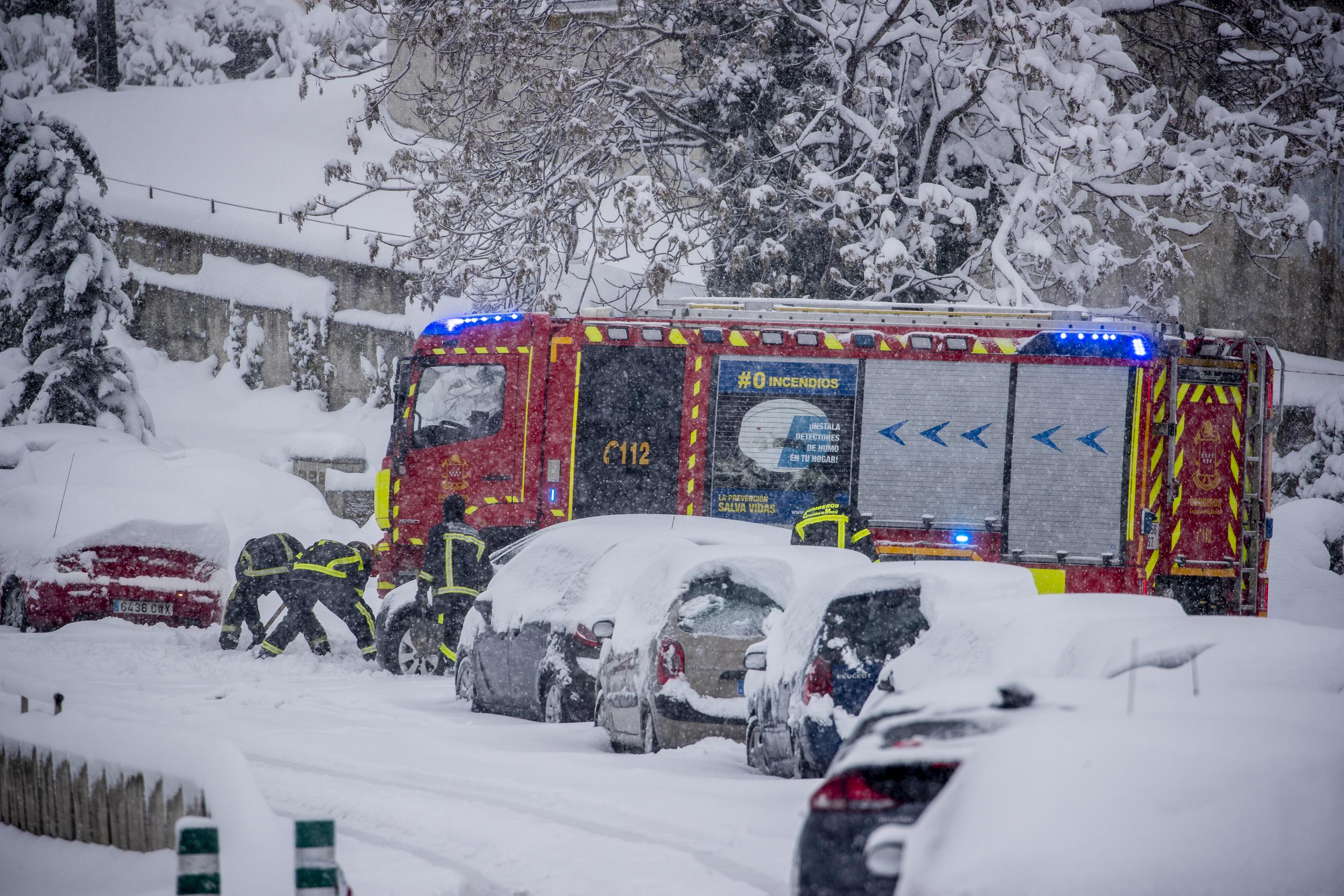 Bomberos intentan remover la nieve de un auto en Rivas Vaciamadrid, España. Una nevada poco usual cubrió el país dejando a miles atrapados en sus carros.